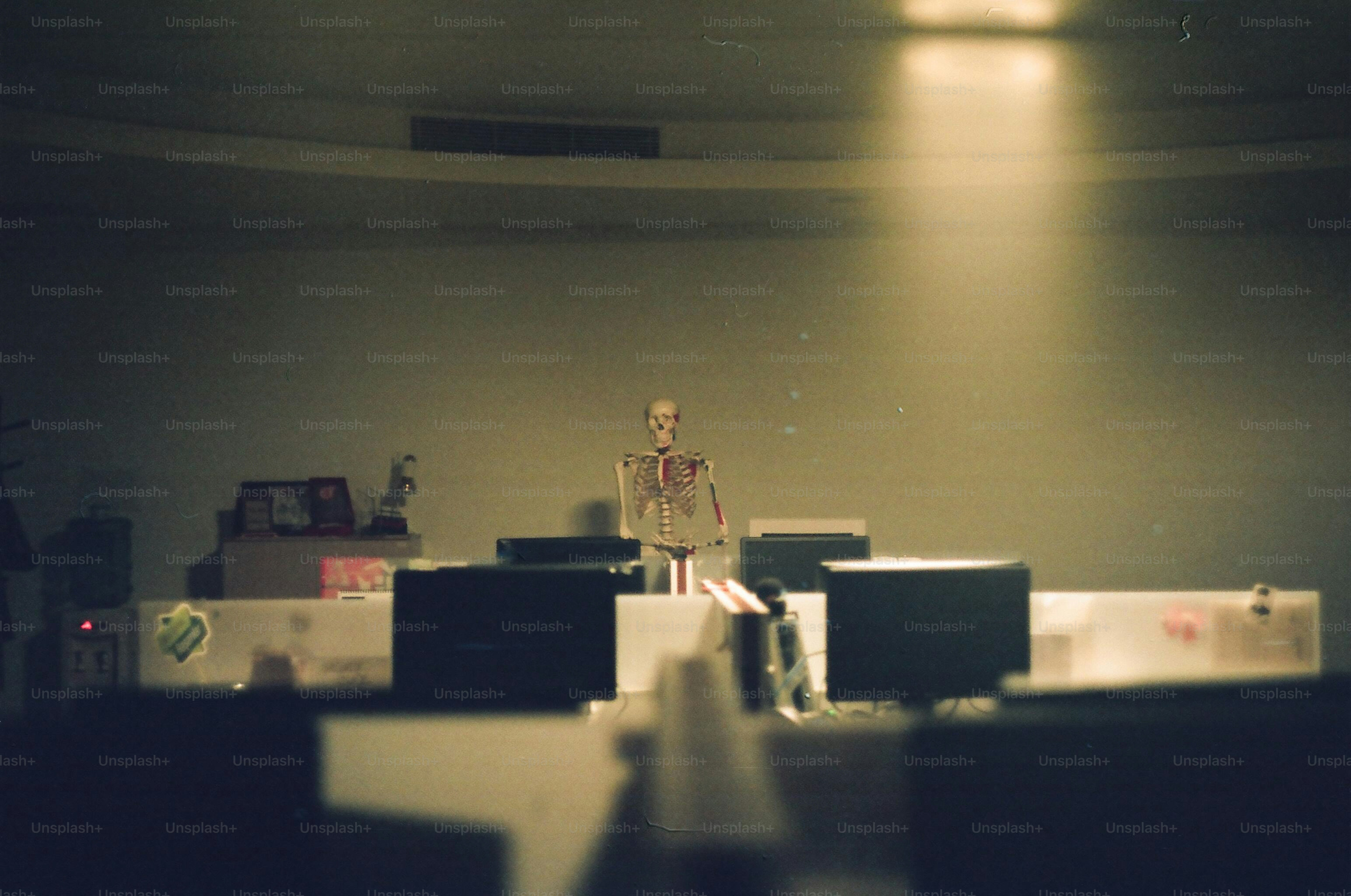A skeleton stands on a platform with monitors.