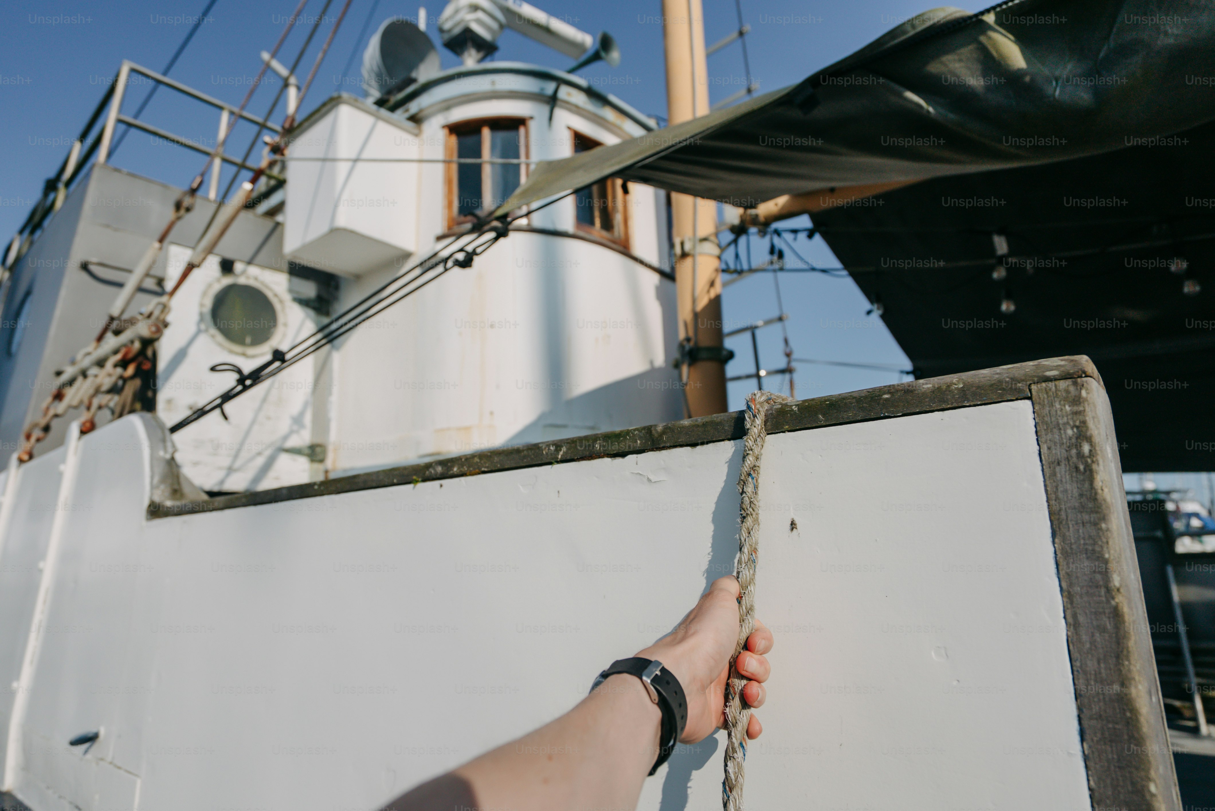 A hand pulls a rope on a white boat.