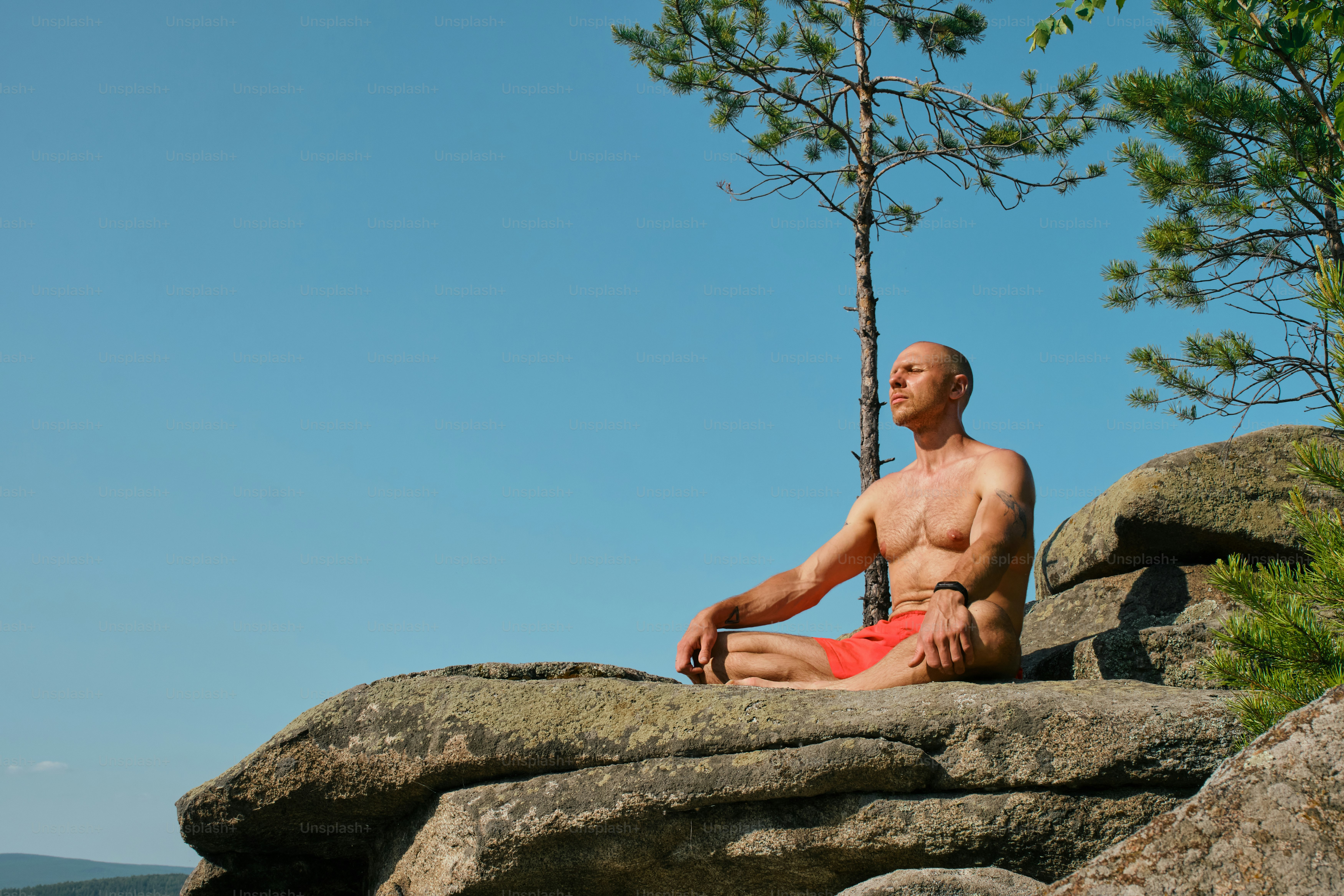 Man meditates on a rock in the sunshine.