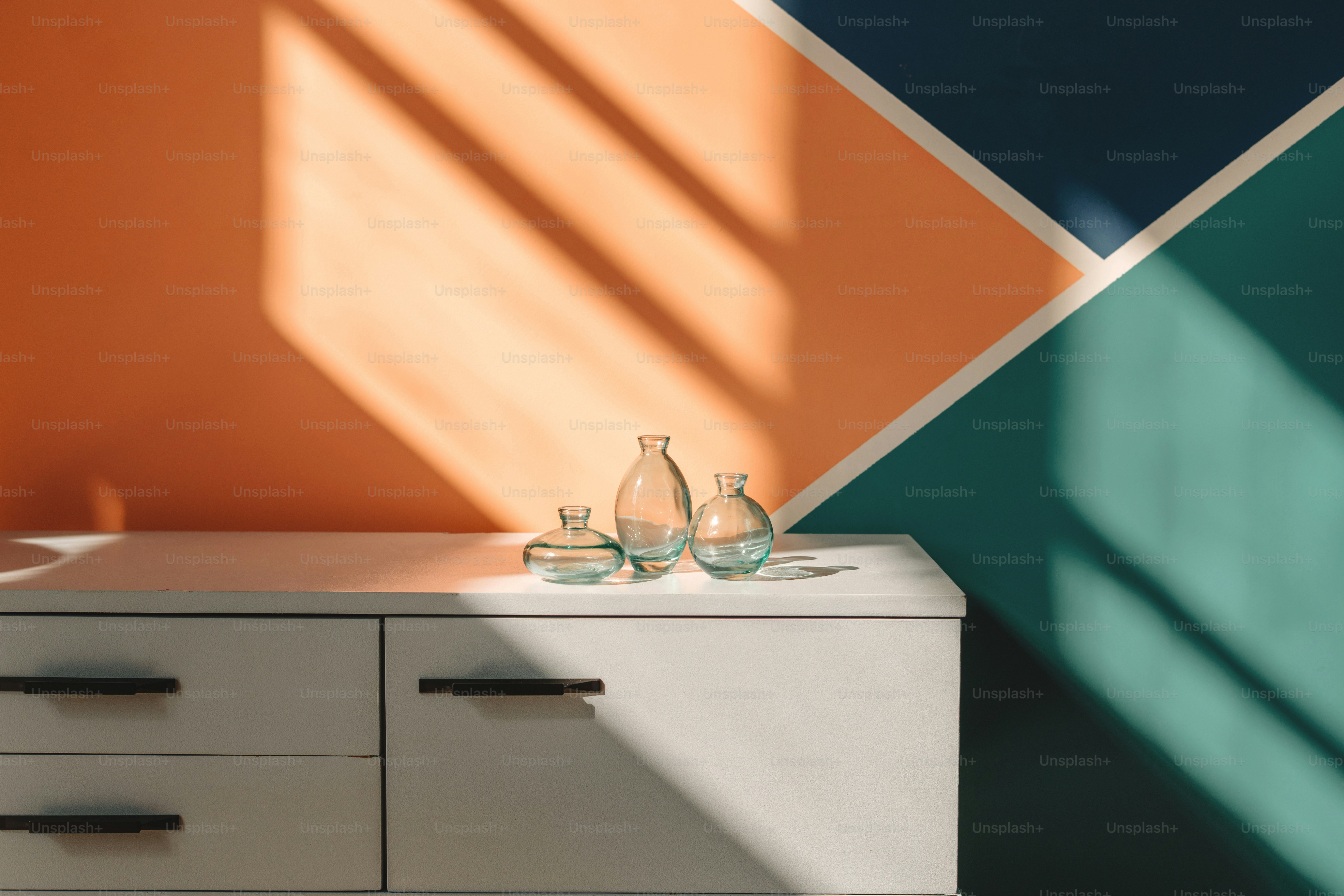 Vases sit on a white cabinet in sunlit room.