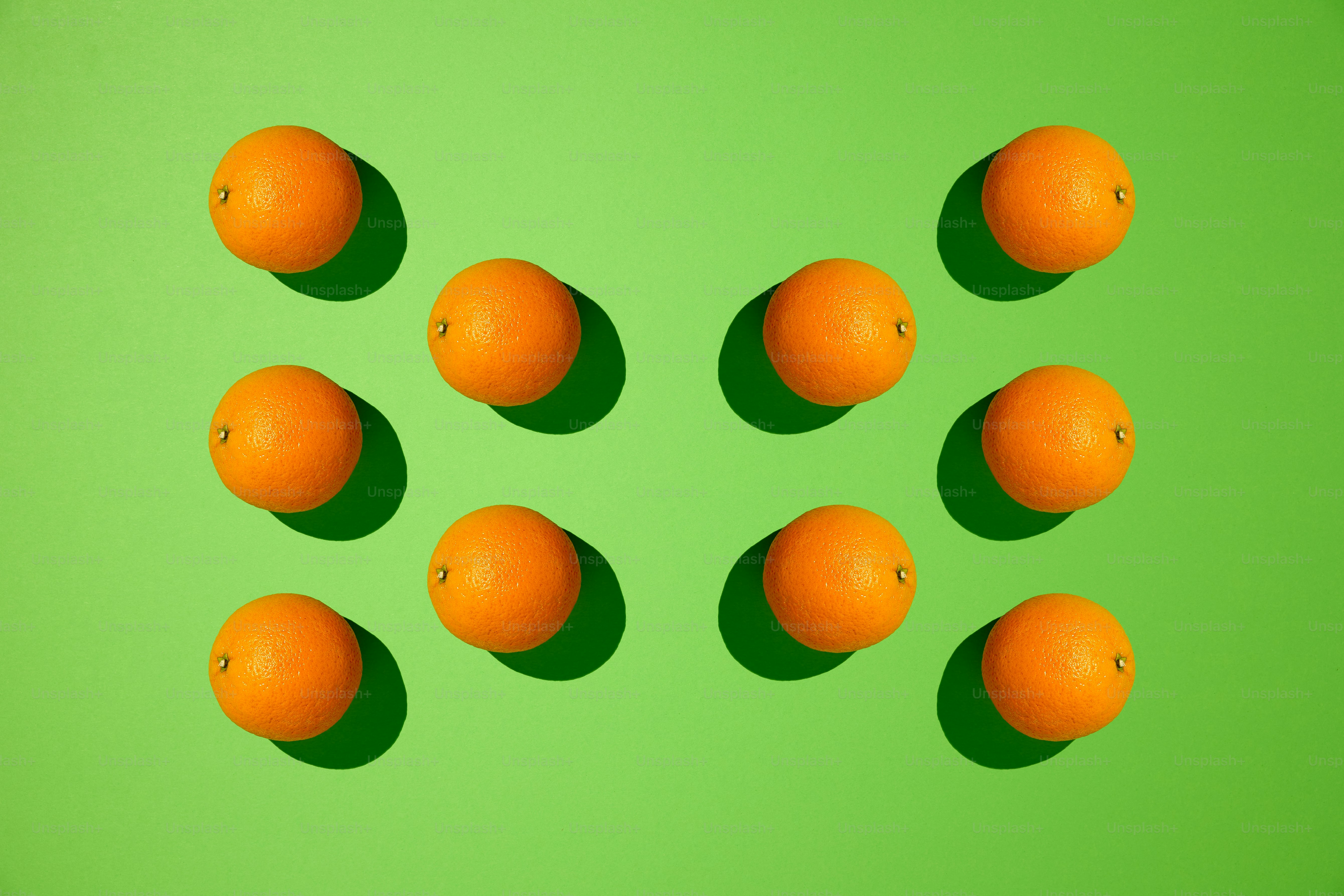Ten oranges are arranged on a green surface.