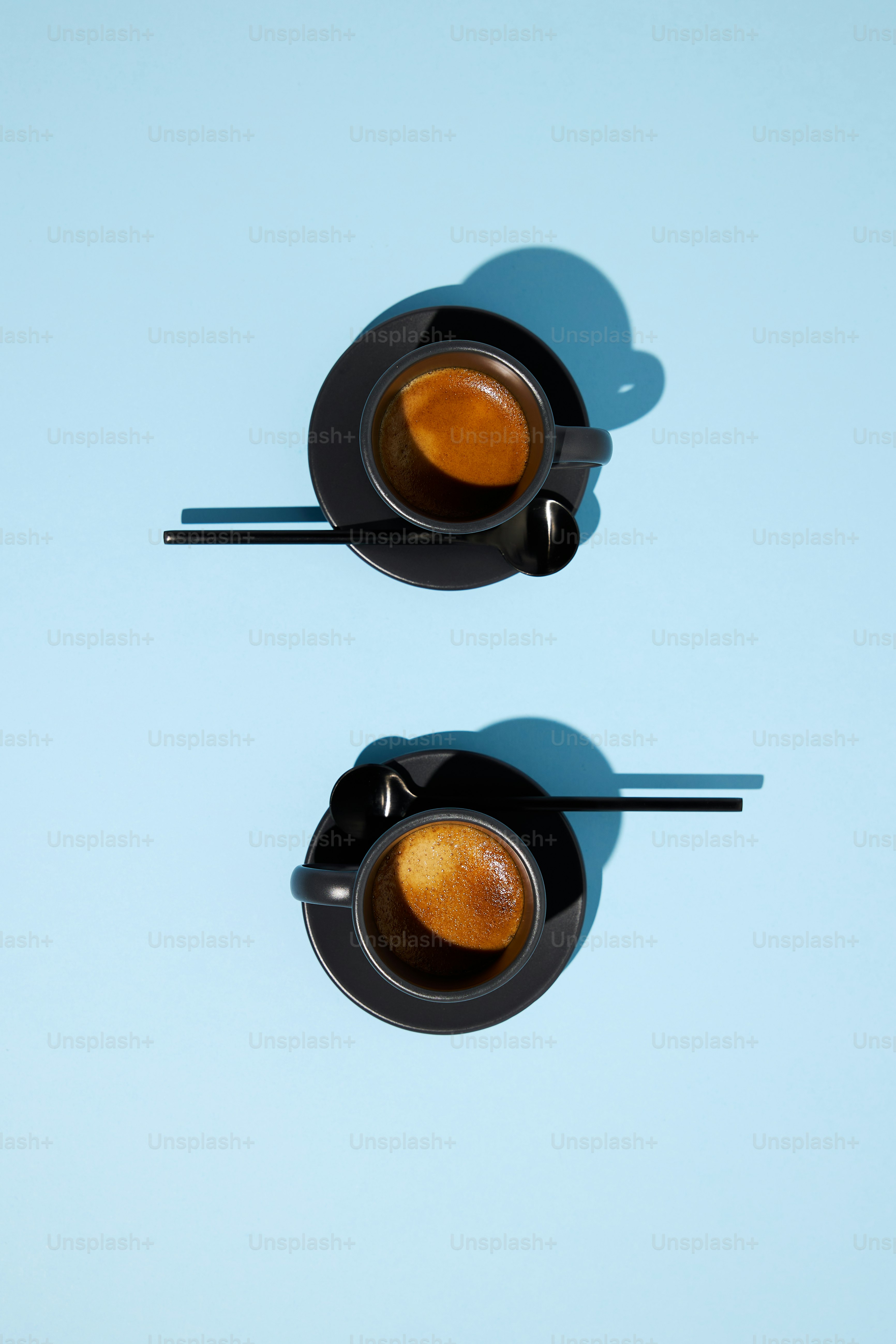 Zwei Espressotassen auf hellblauer Oberfläche.