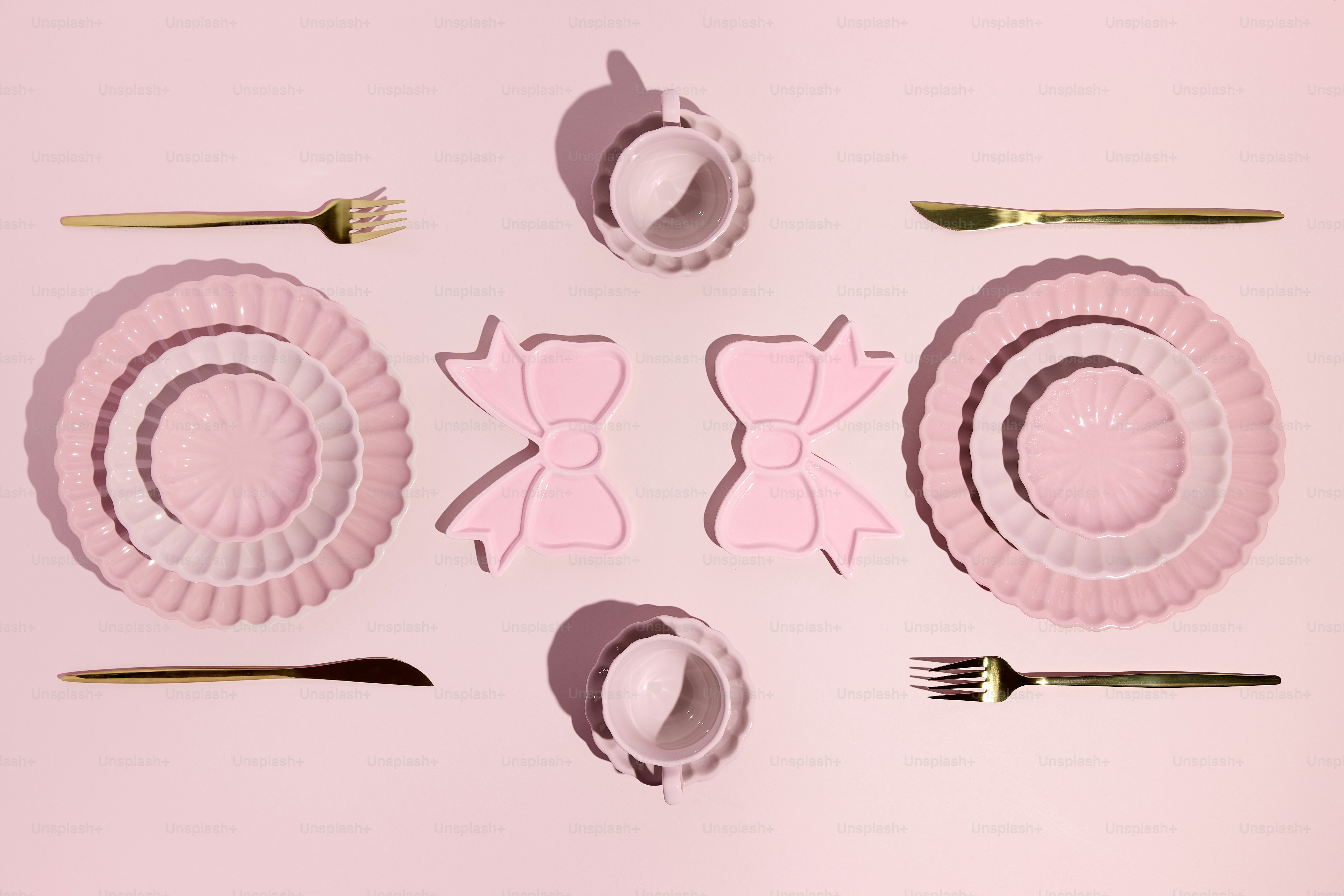 Pink tableware arranged on a pink background.