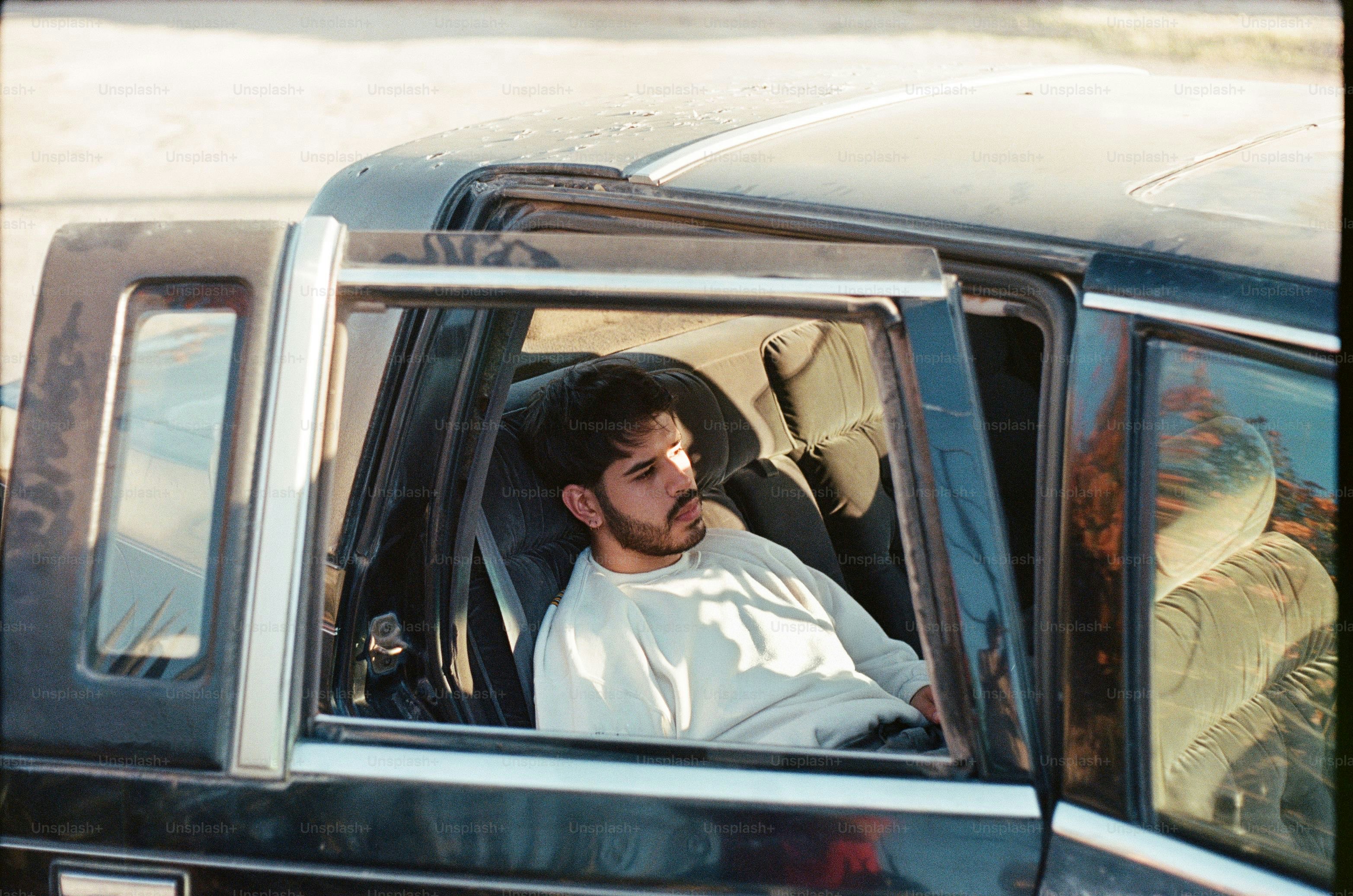 A man sits in a car looking outside.