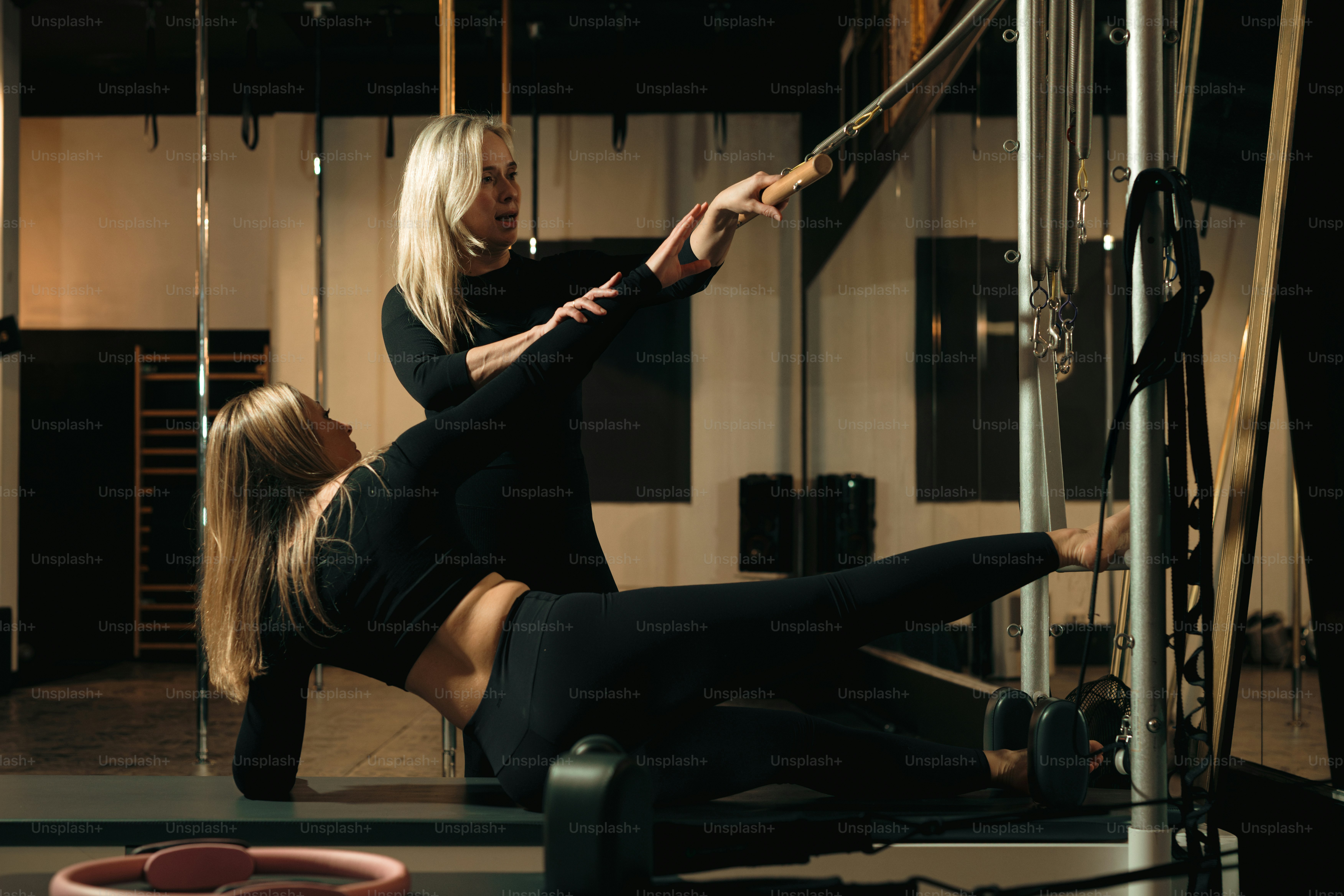 Pilates instructor guides a client during an exercise. photo – Fitness ...