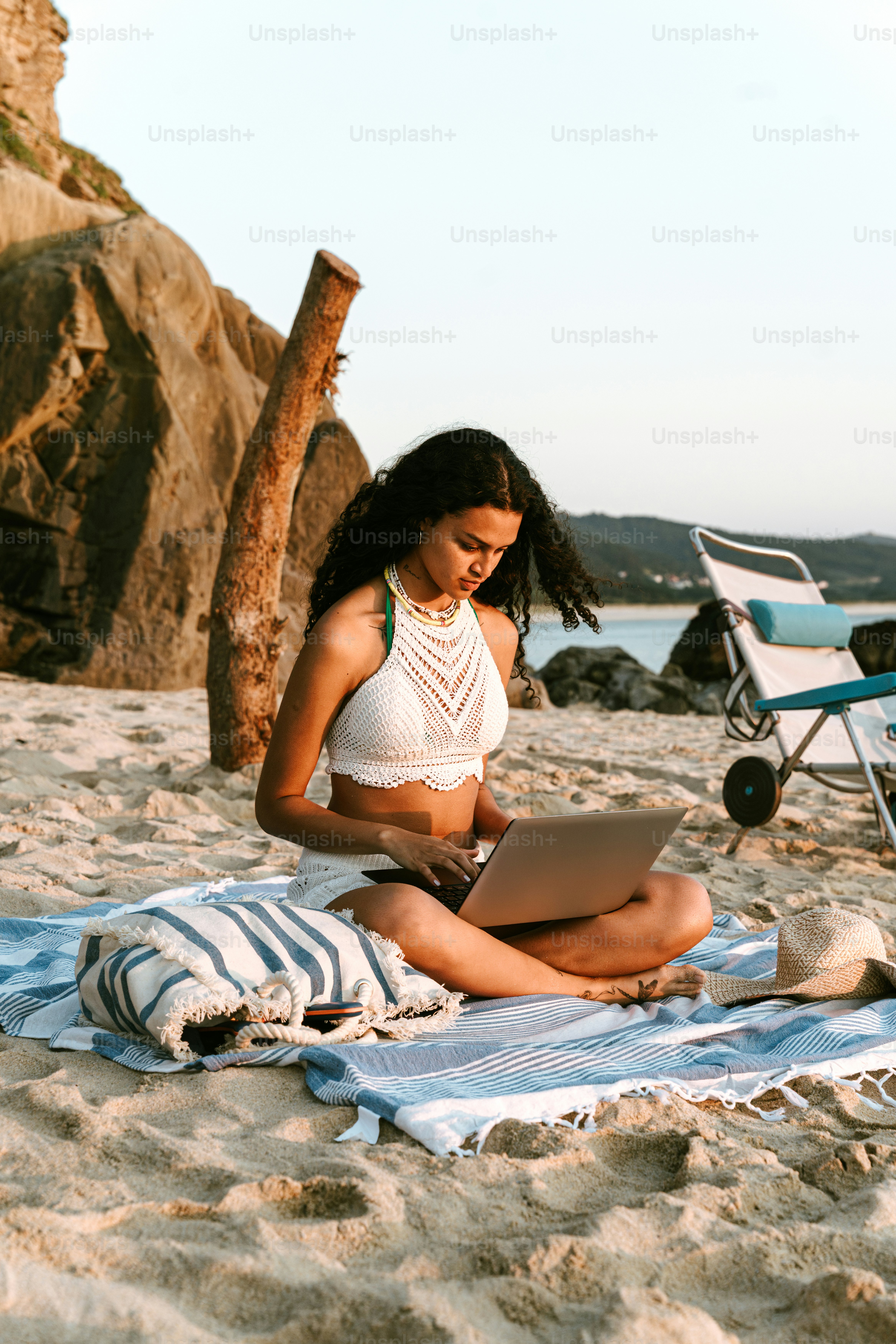 Frau arbeitet am Strand an ihrem Laptop.