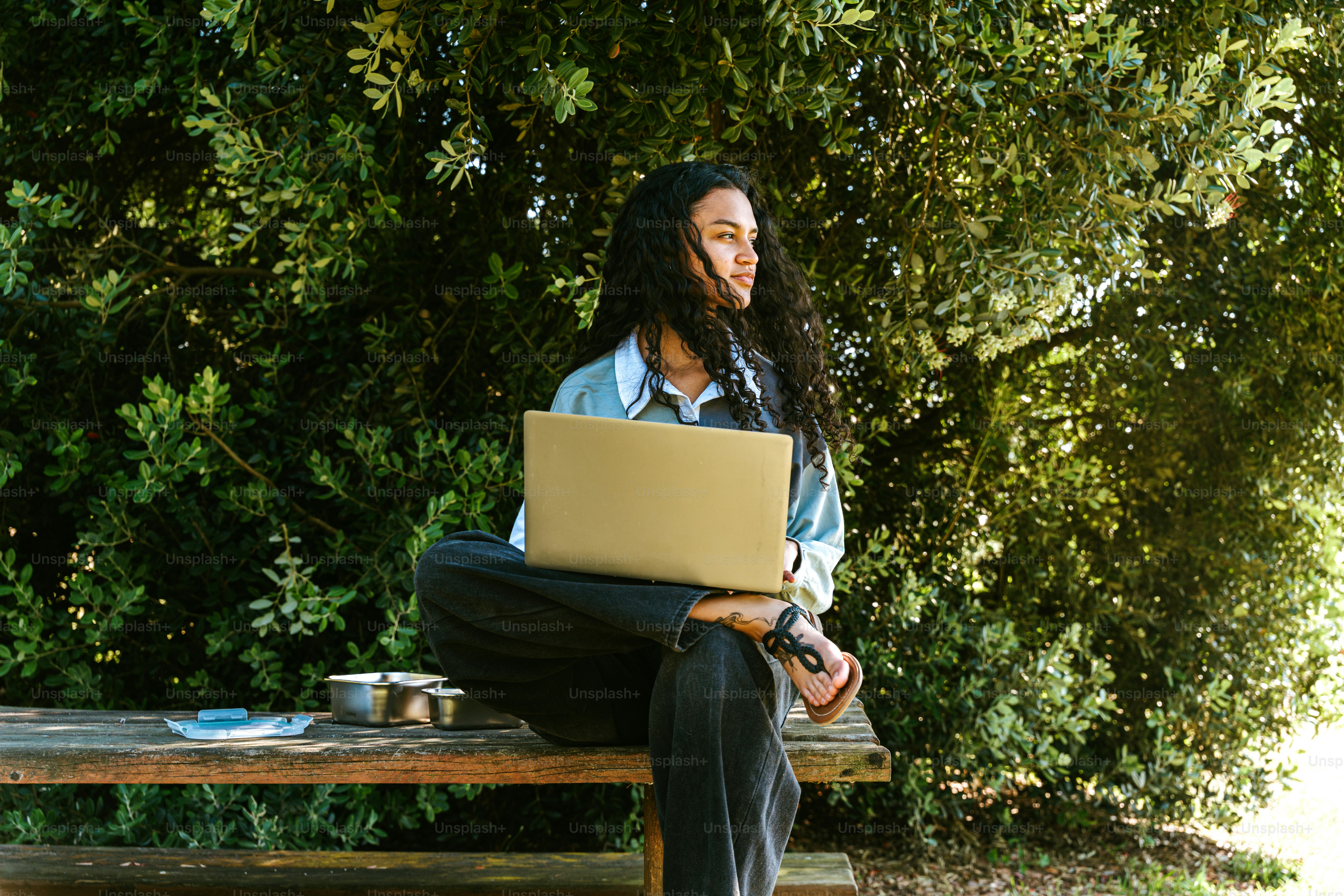 Woman works on a laptop outdoors, enjoying nature.