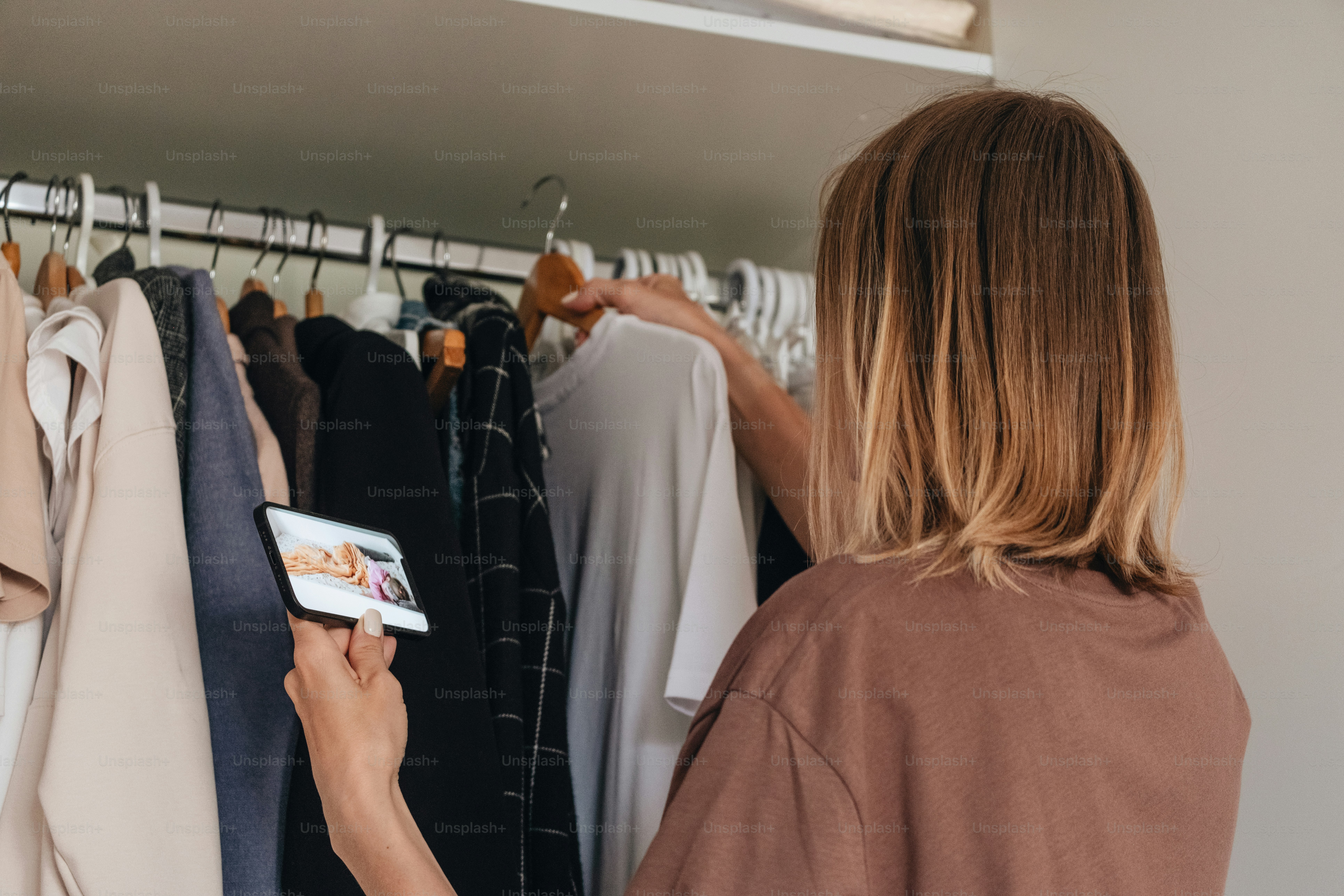 Woman chooses clothes in her closet.
