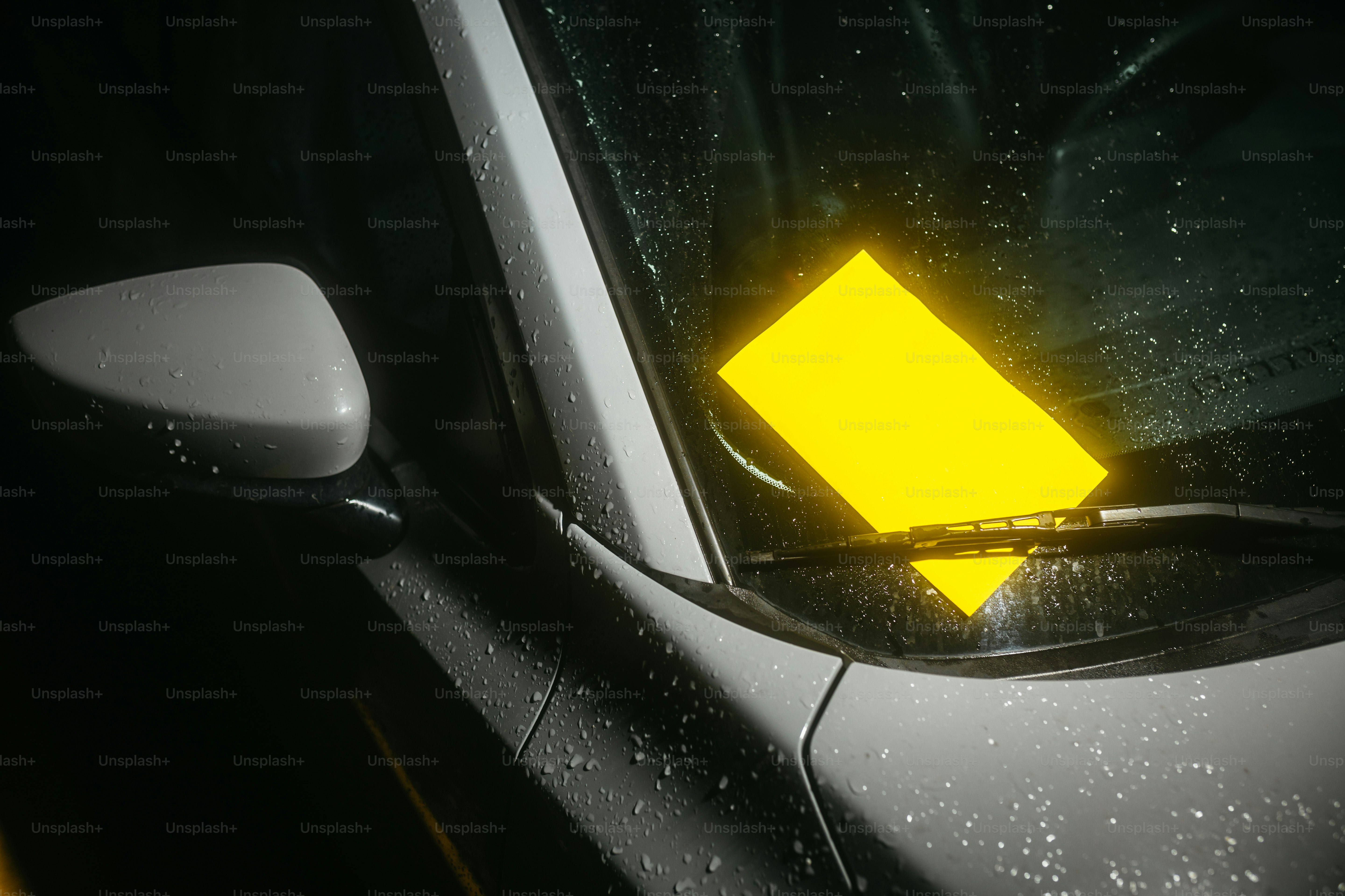 A parking ticket is illuminated on a car windshield.