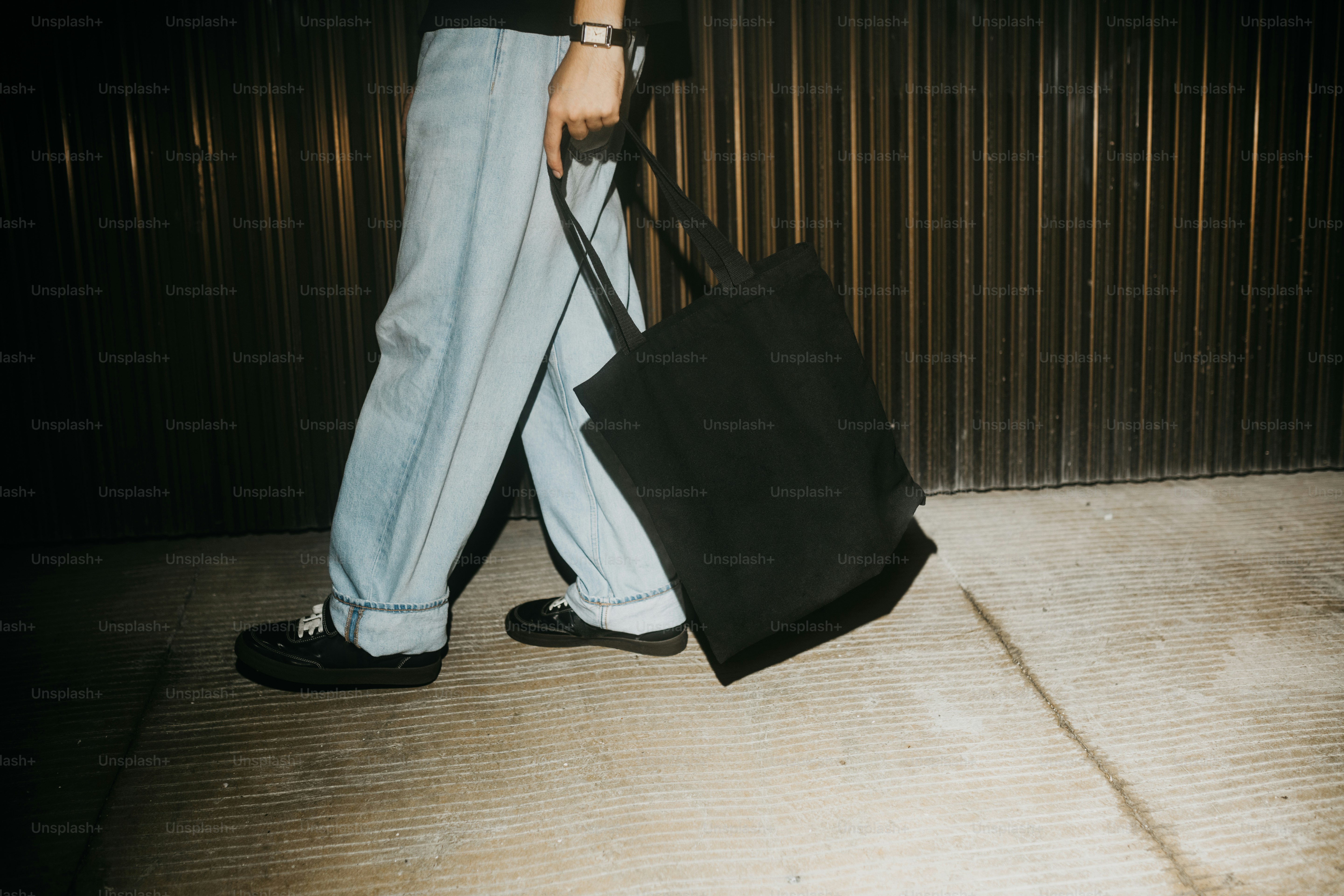 Person walks holding a tote bag.