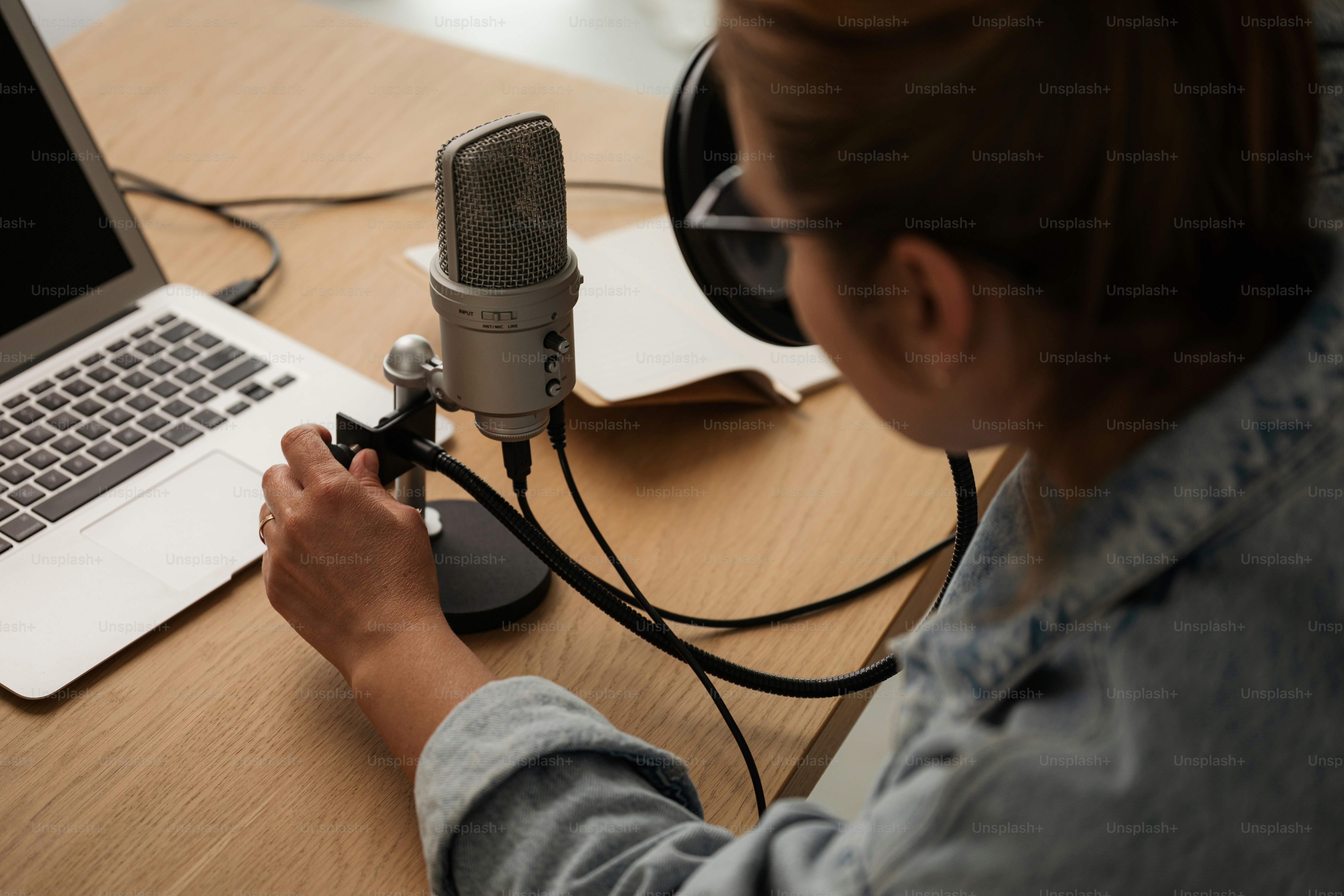 Person recording a podcast with microphone and laptop in a studio