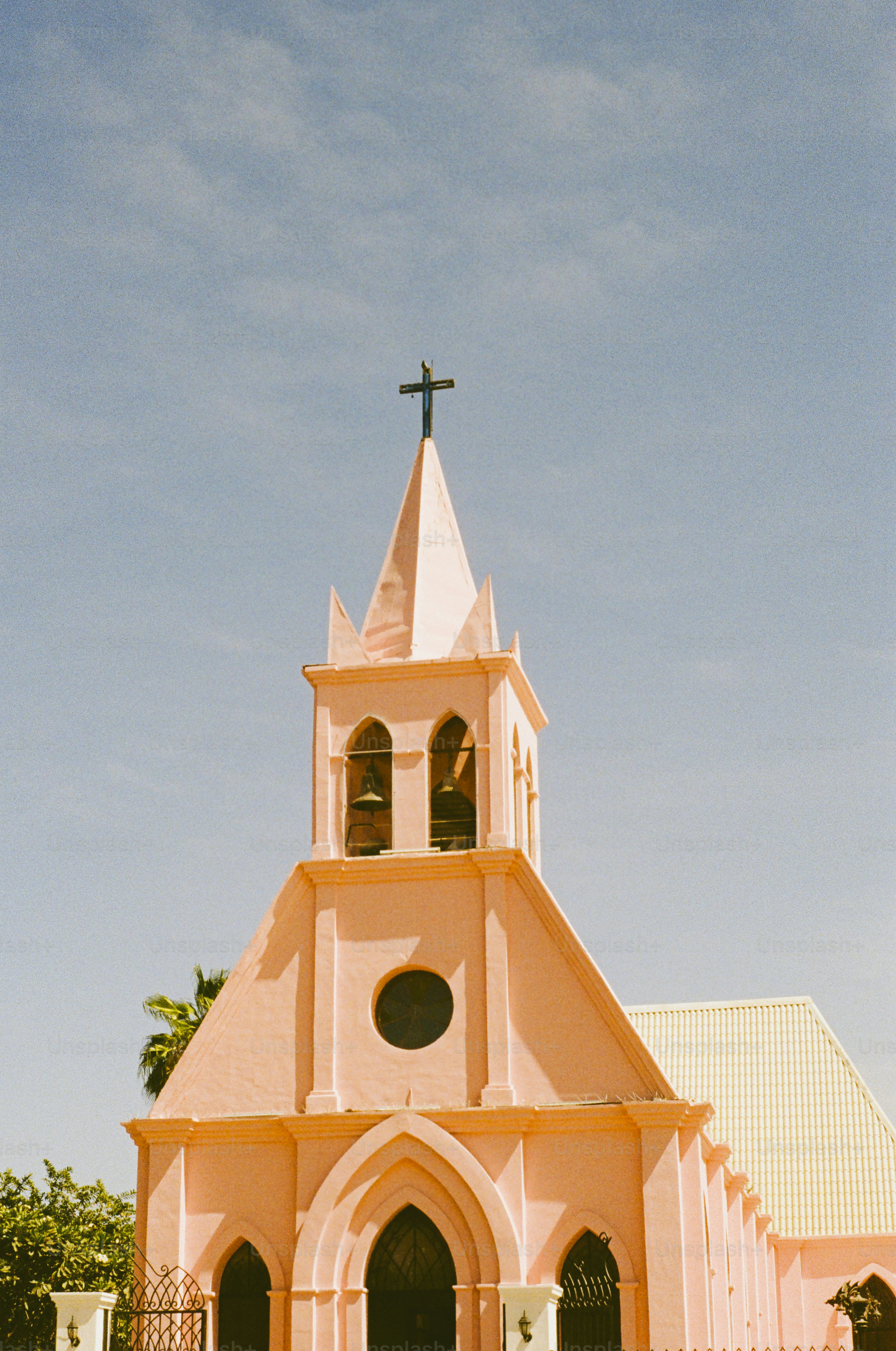 A pink church stands tall under a bright blue sky.