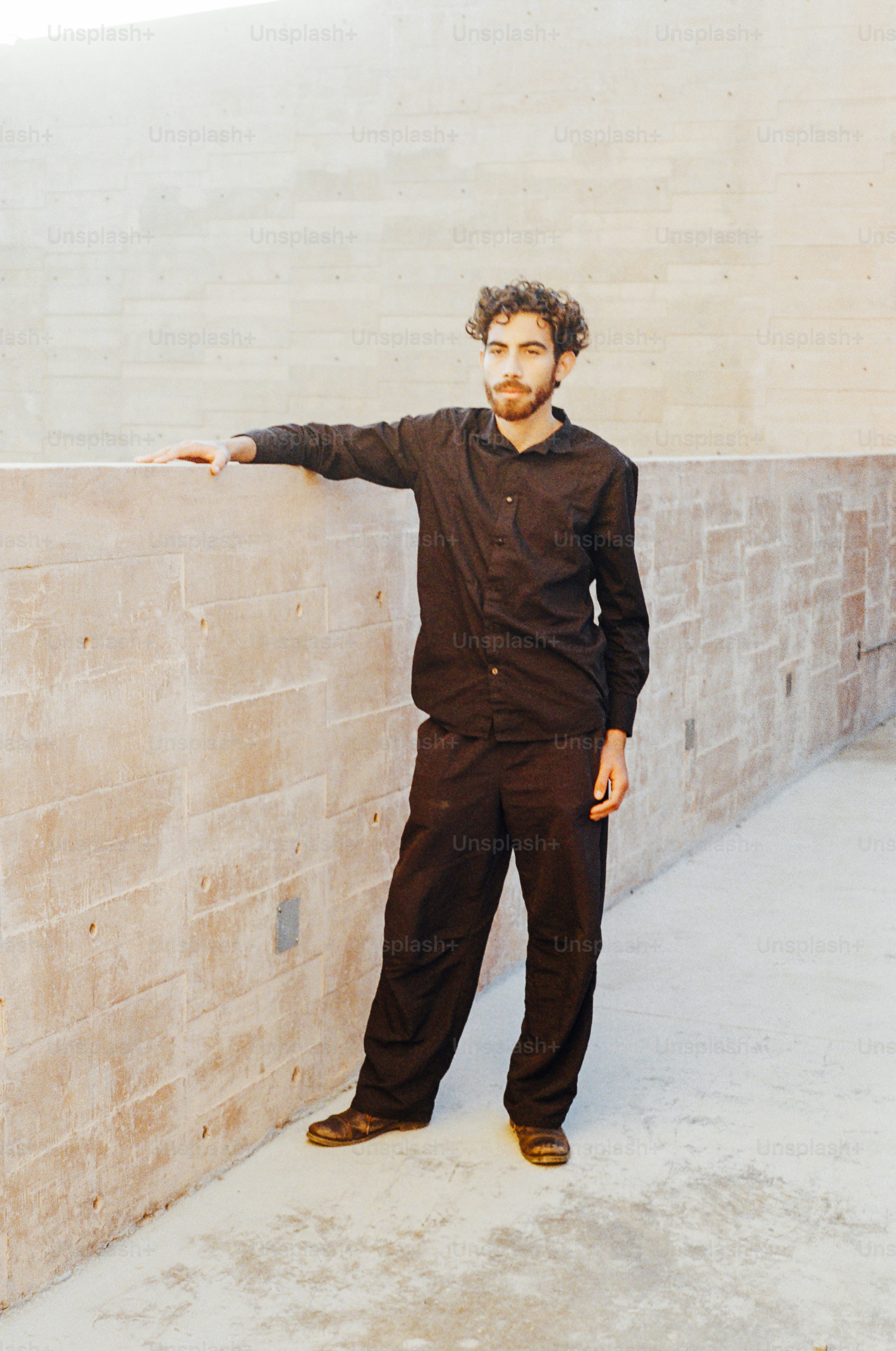 A man leans against a concrete wall.