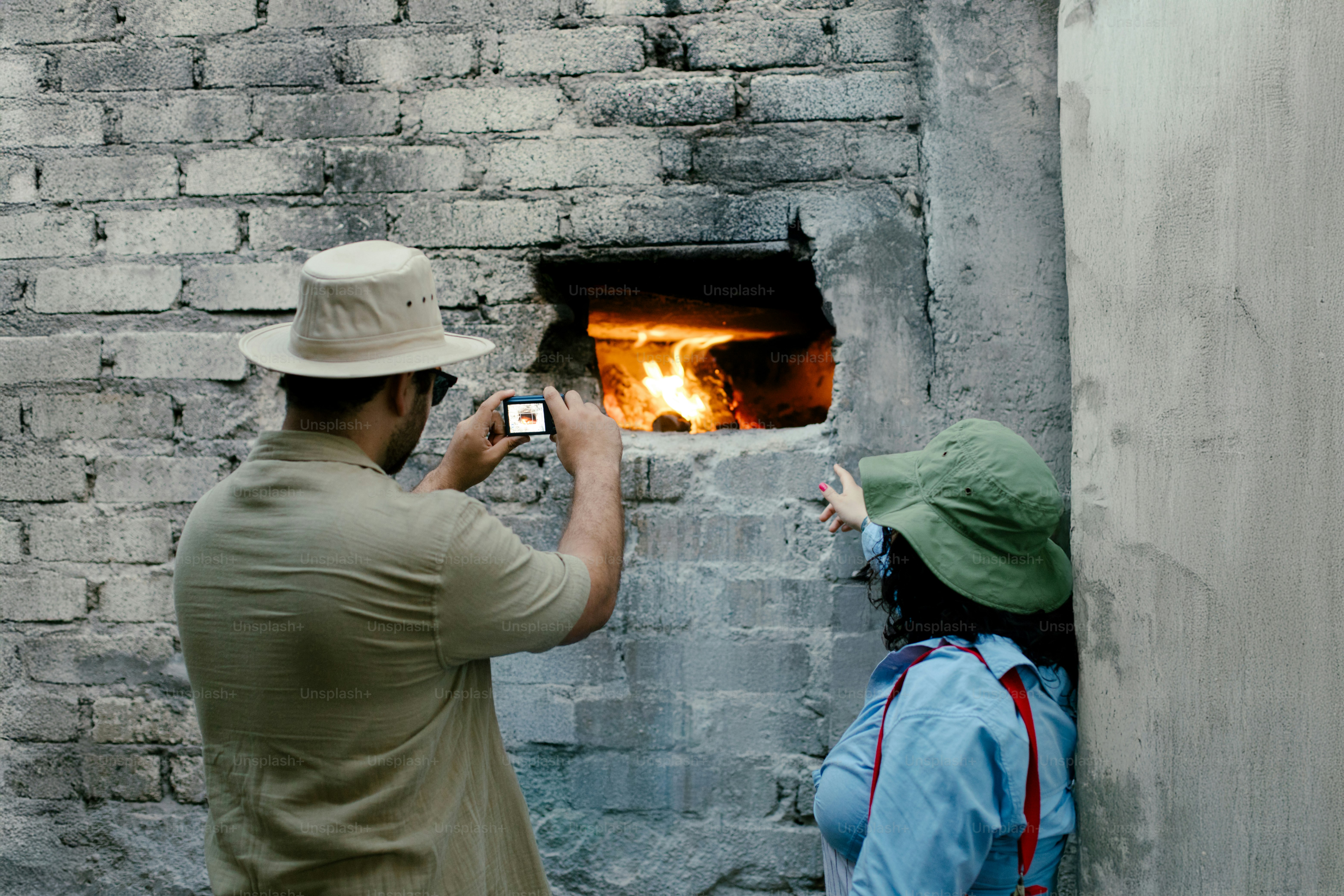 Deux personnes prennent des photos d’un feu de four en briques.