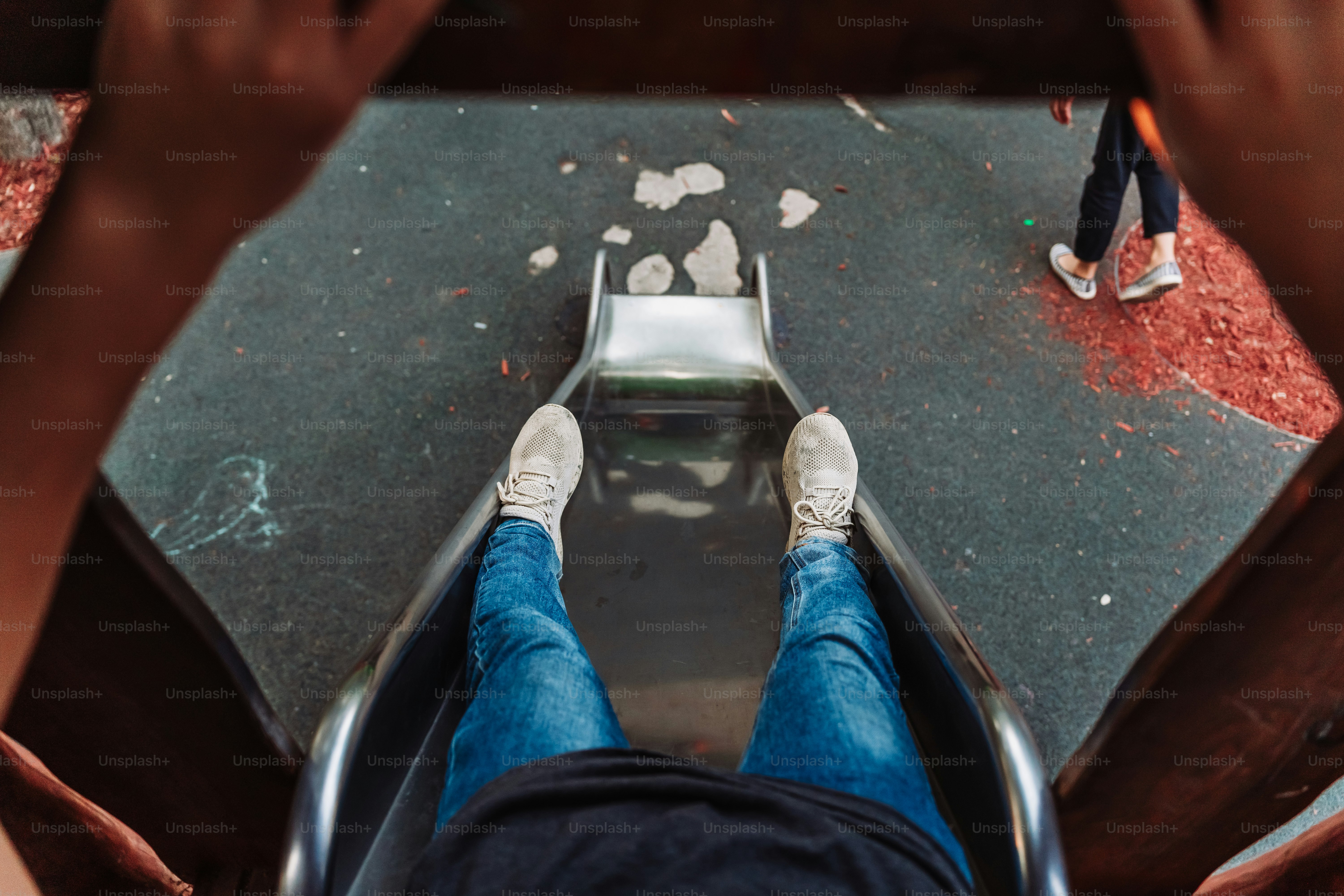La persona se desliza por un tobogán del patio de recreo.