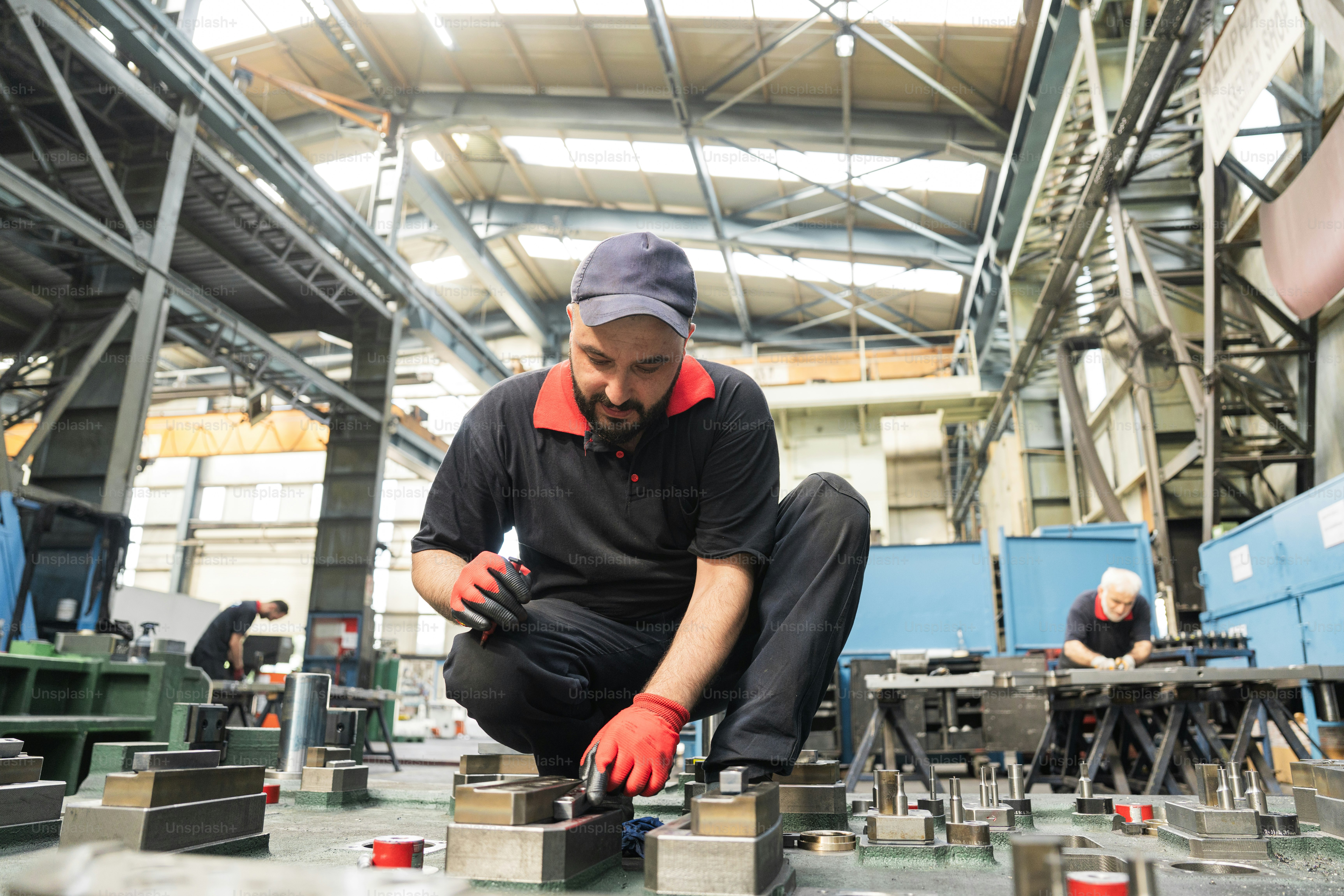 Un ouvrier d’une usine examine des pièces métalliques.
