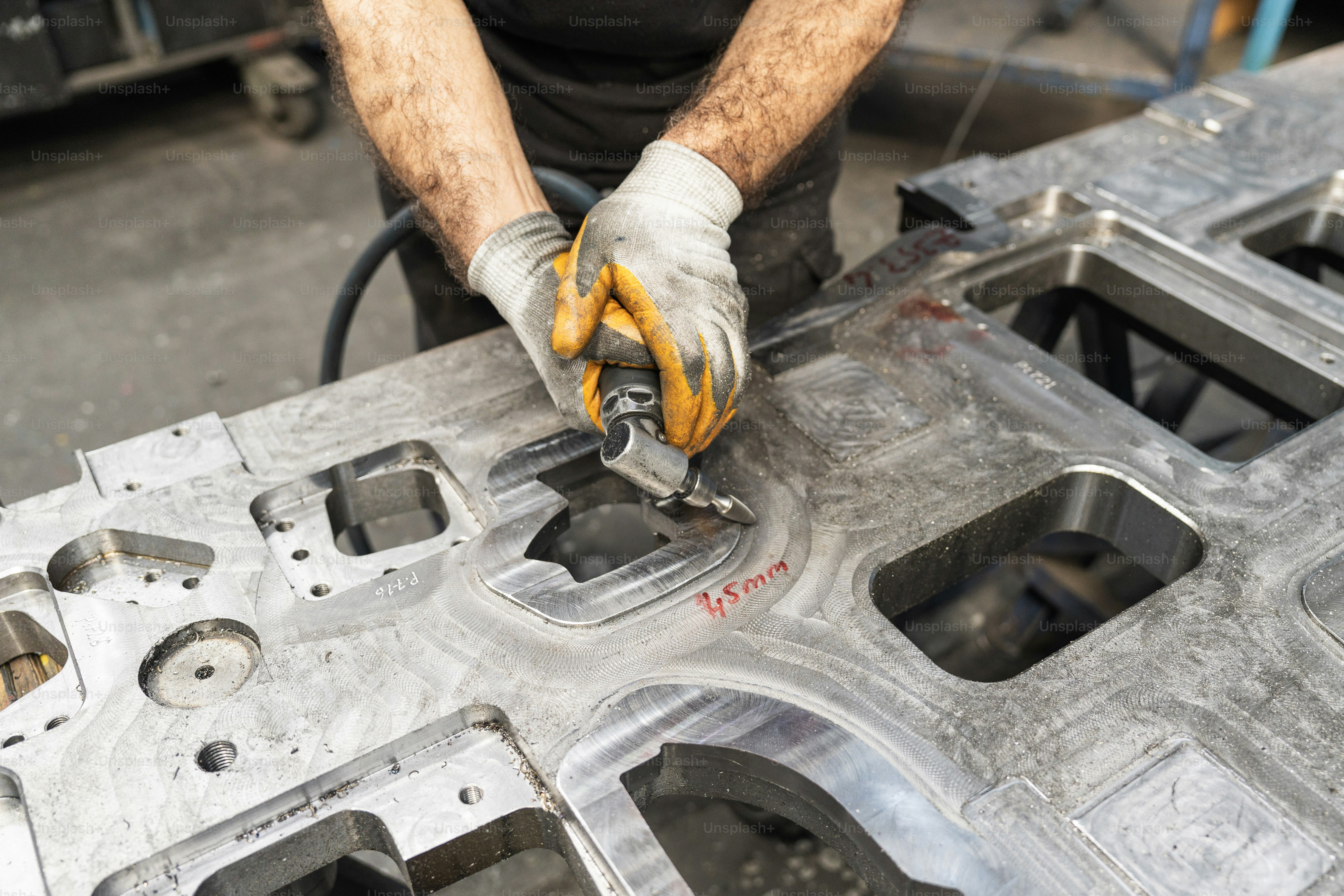 Un ouvrier meut sur un grand moule métallique.