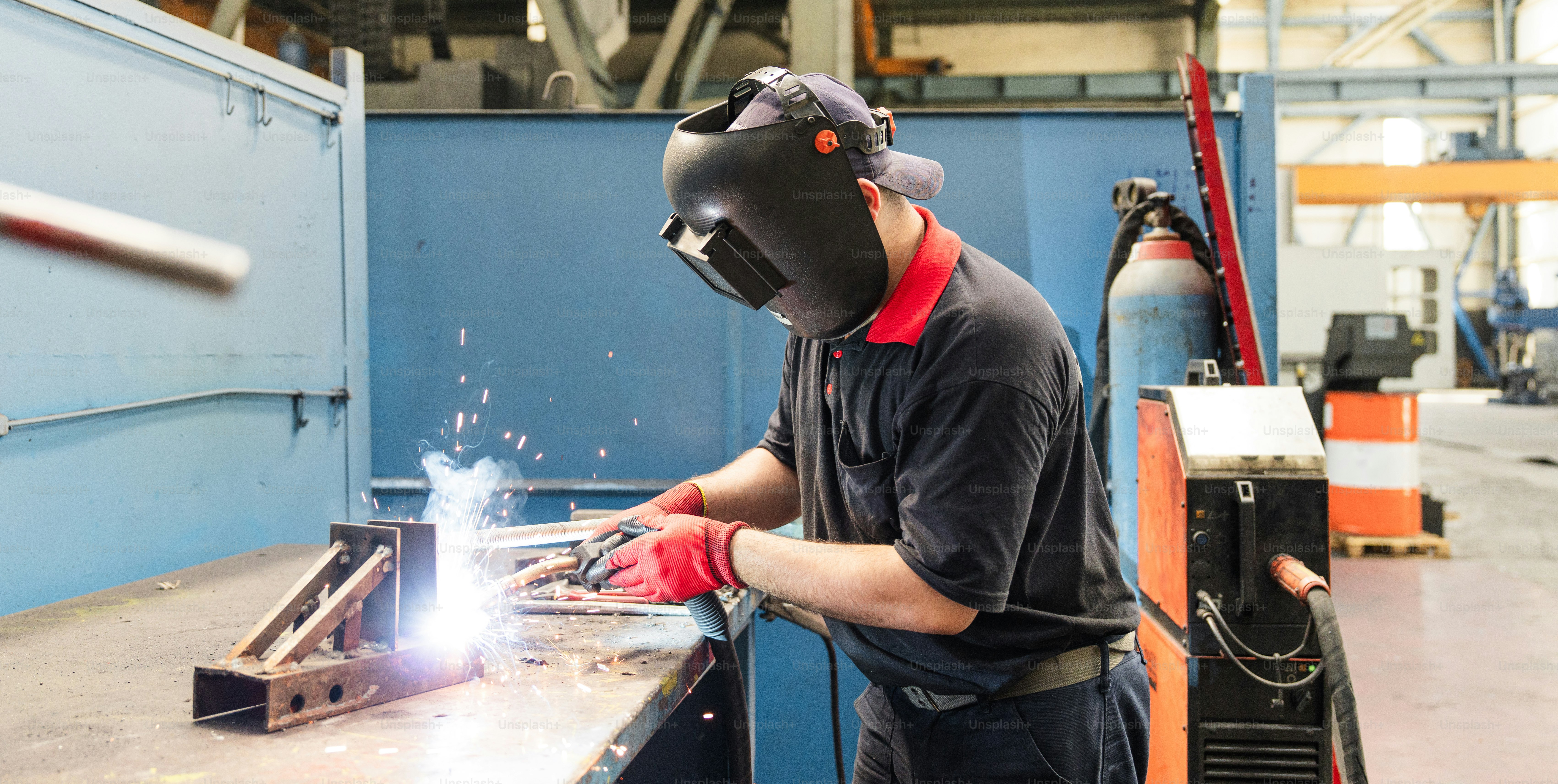 A welder is welding metal in a workshop.
