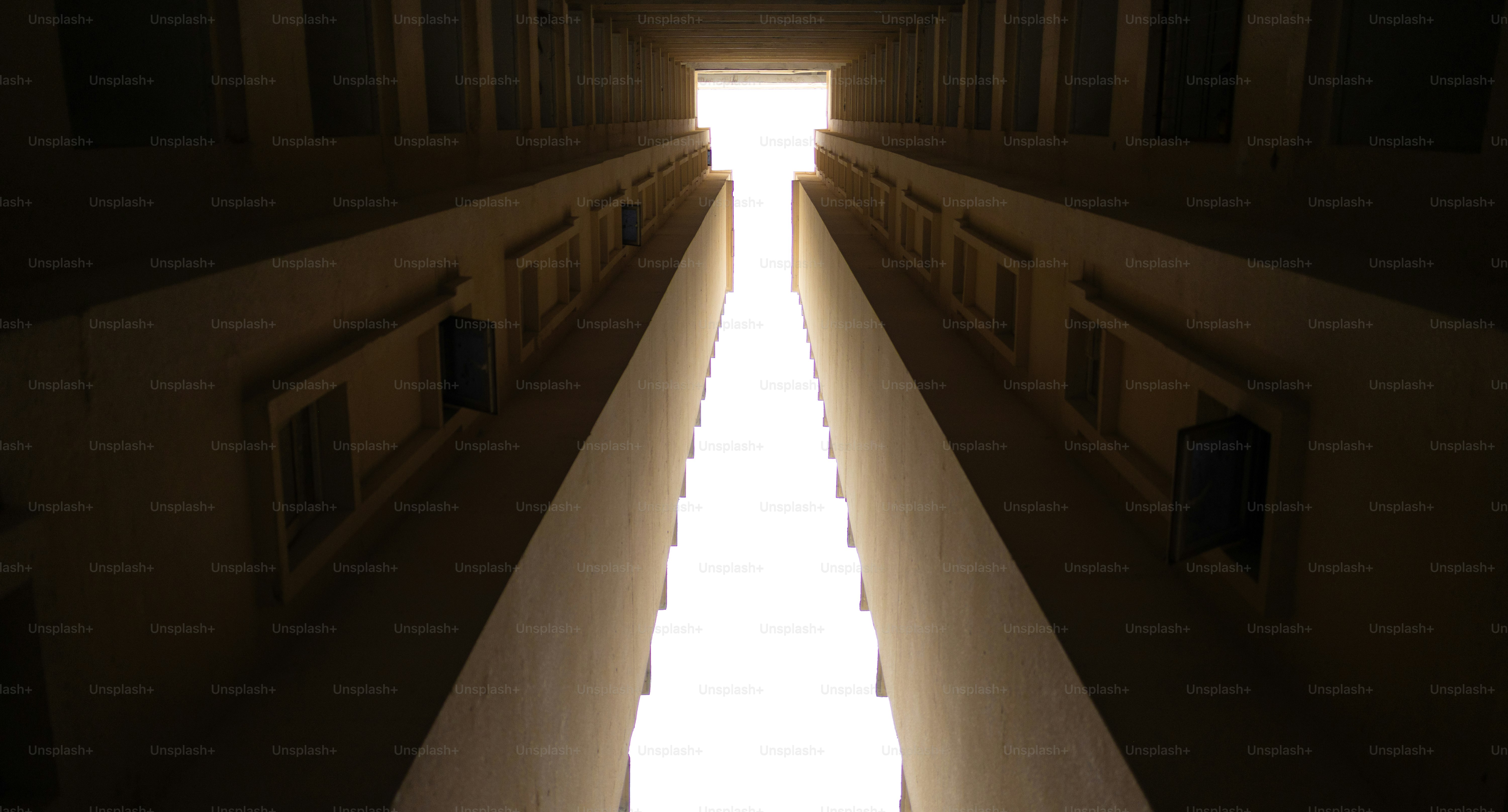 Buildings converge towards bright light in the sky.