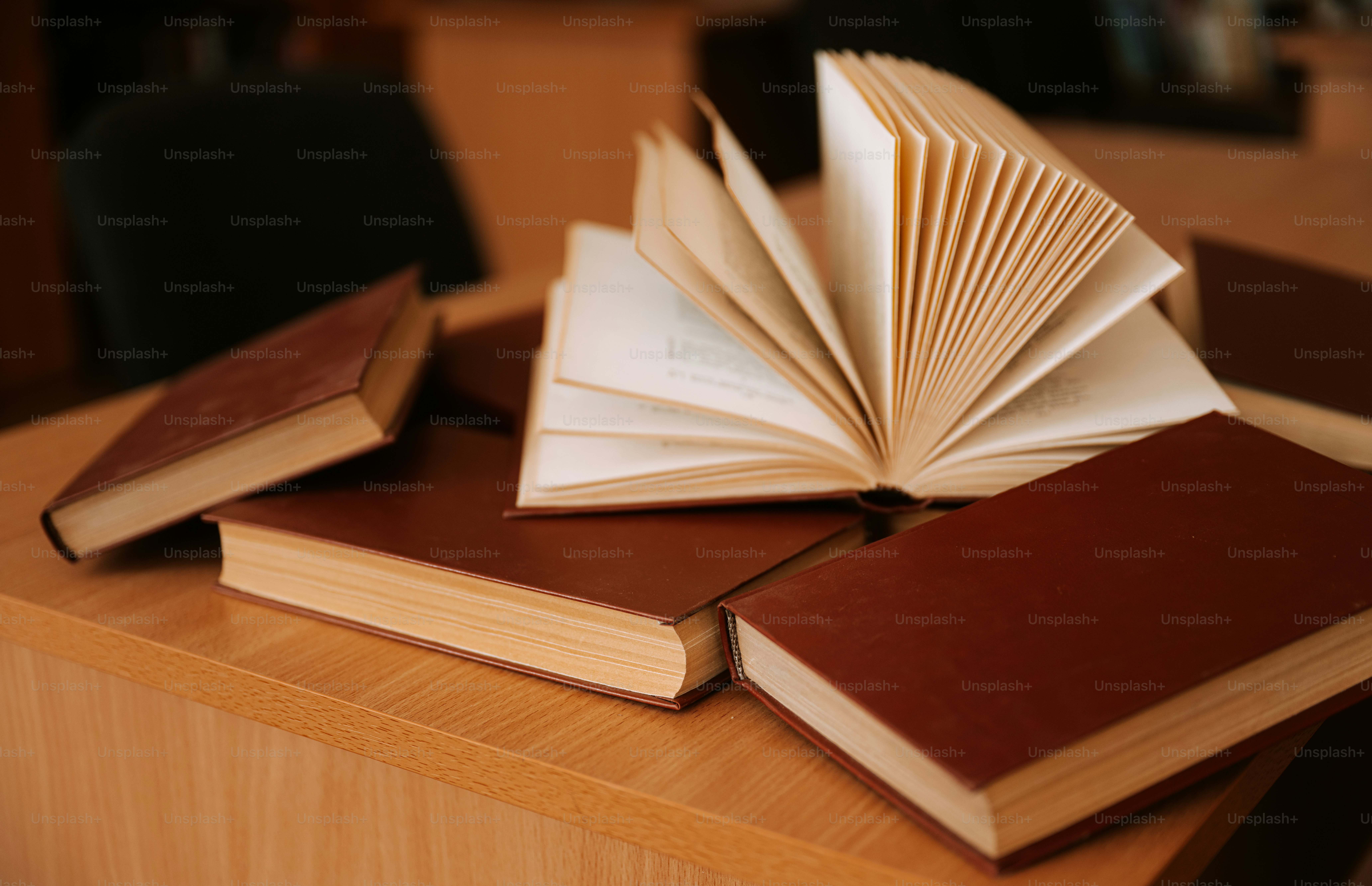 Books are stacked on a wooden table.