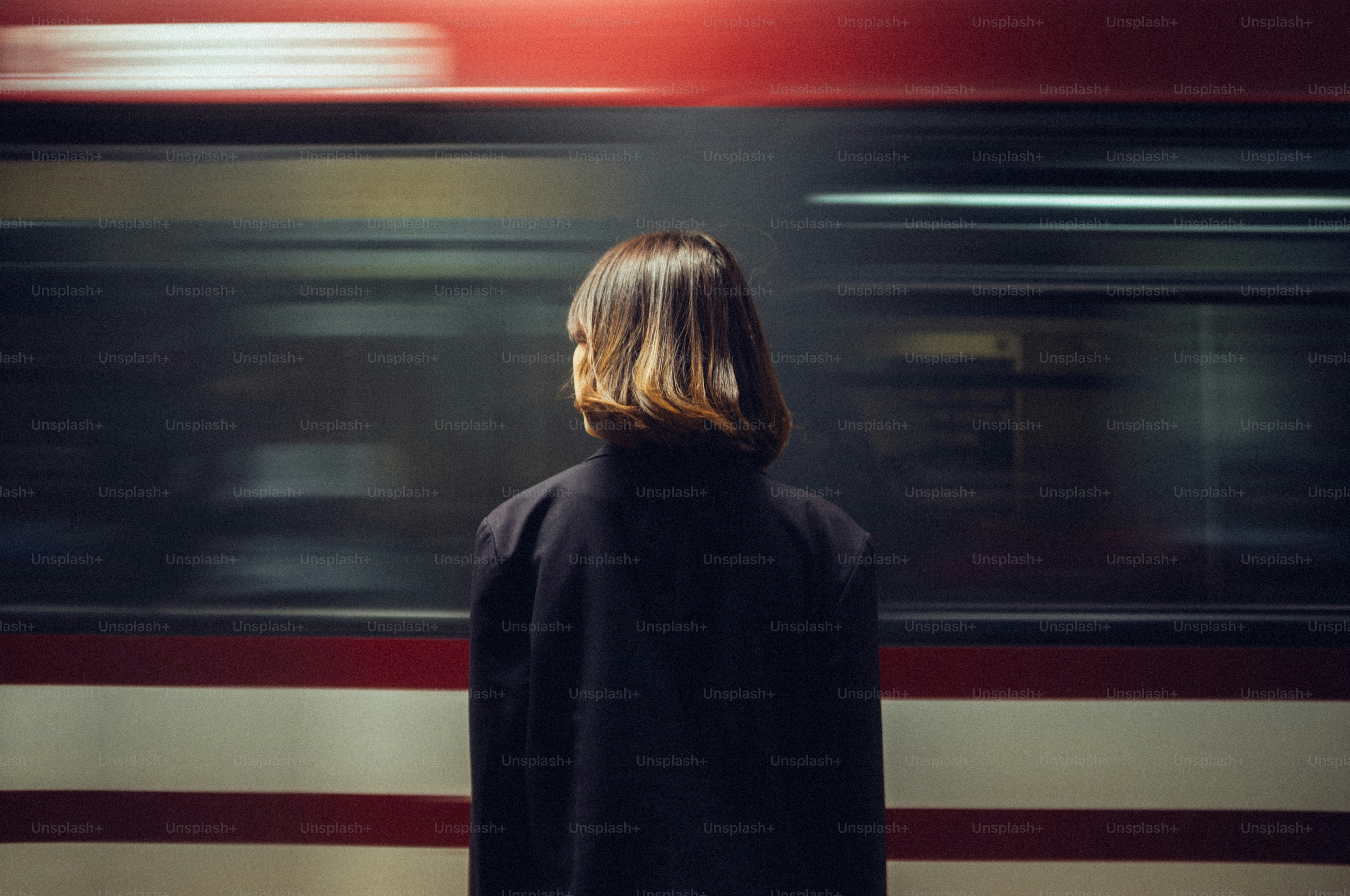Una mujer espera en un andén mientras un tren pasa a toda velocidad.