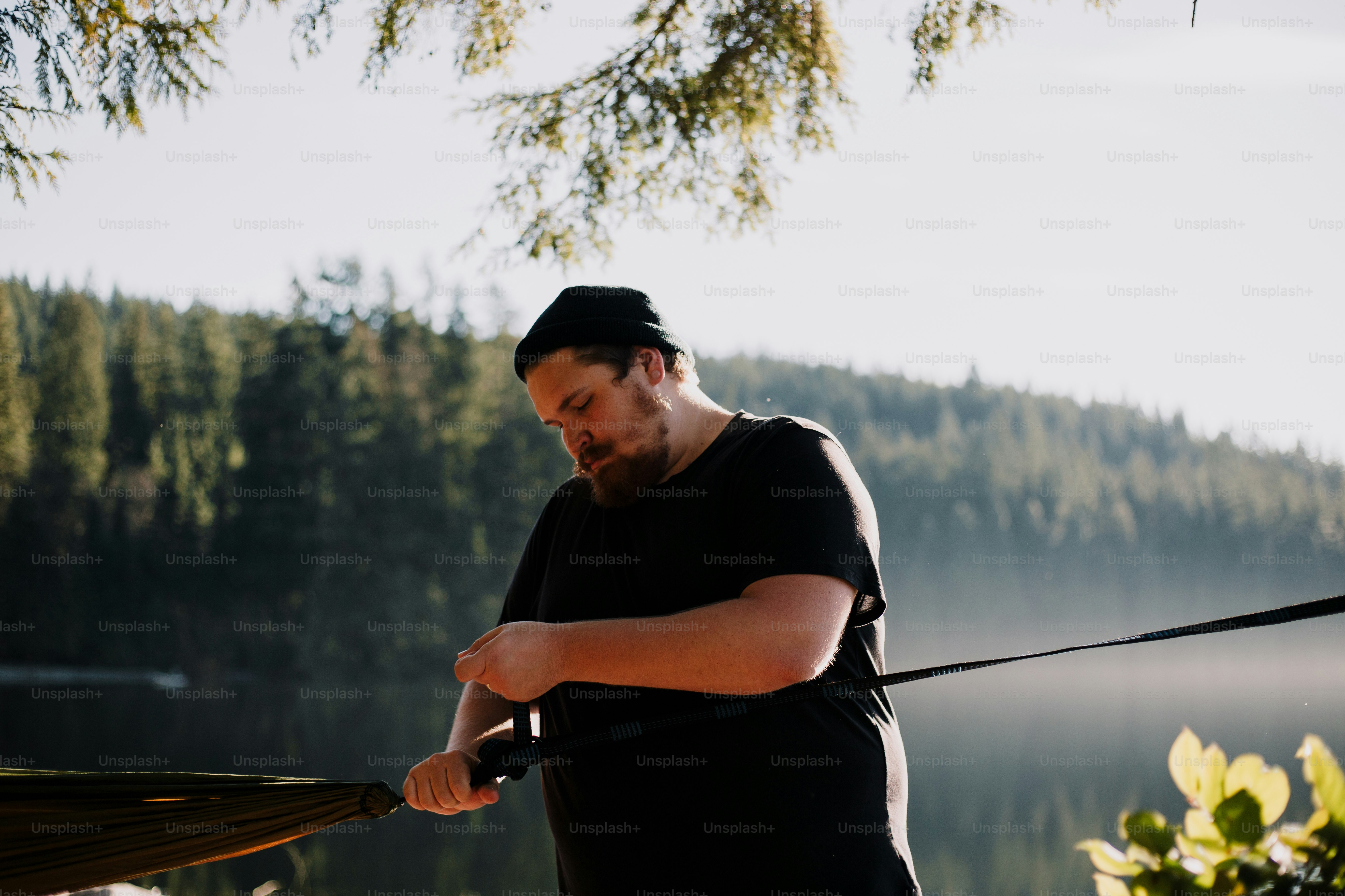 Man sets up a hammock near a lake.