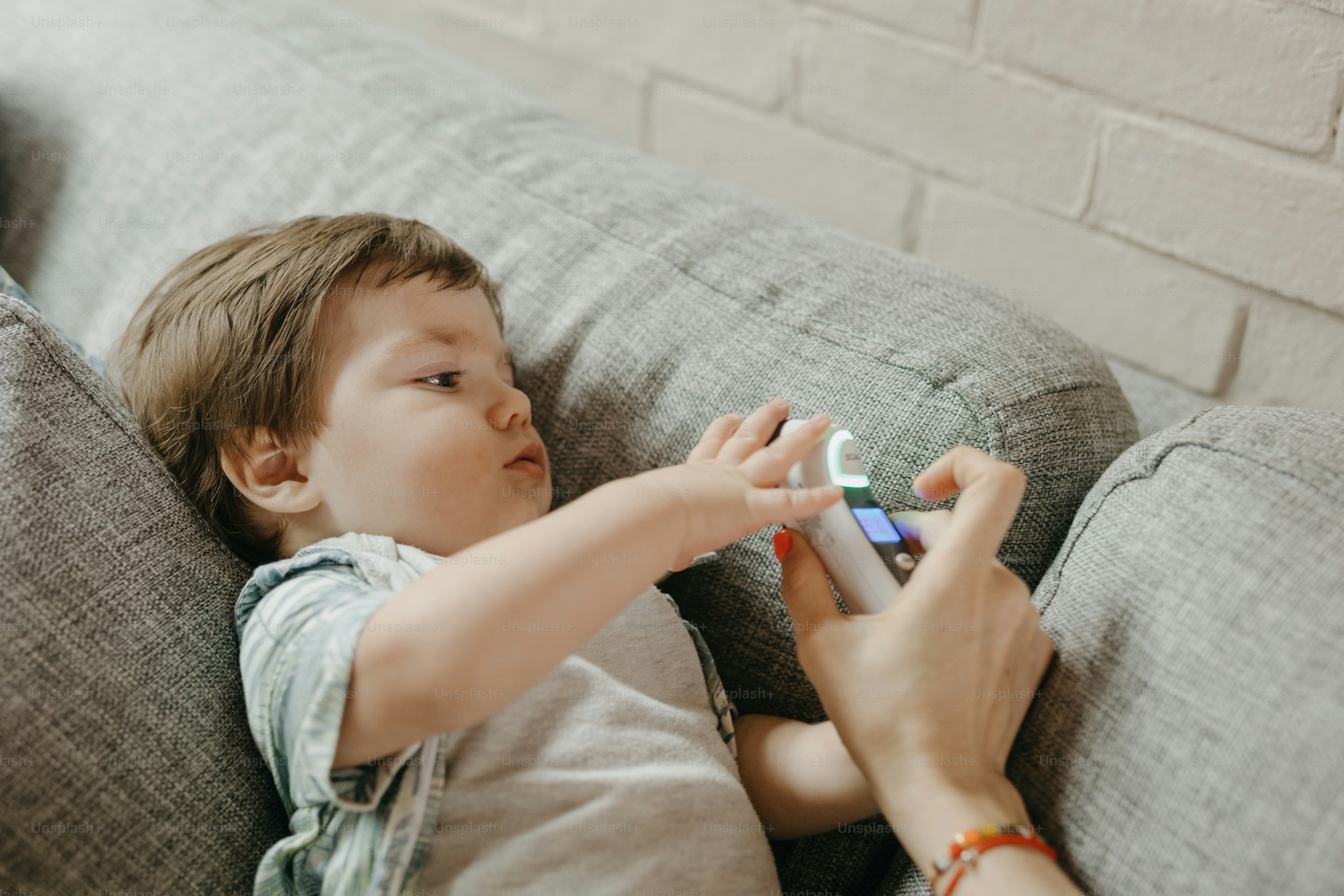 Child plays with a controller on the couch. photo – Technology Image on ...