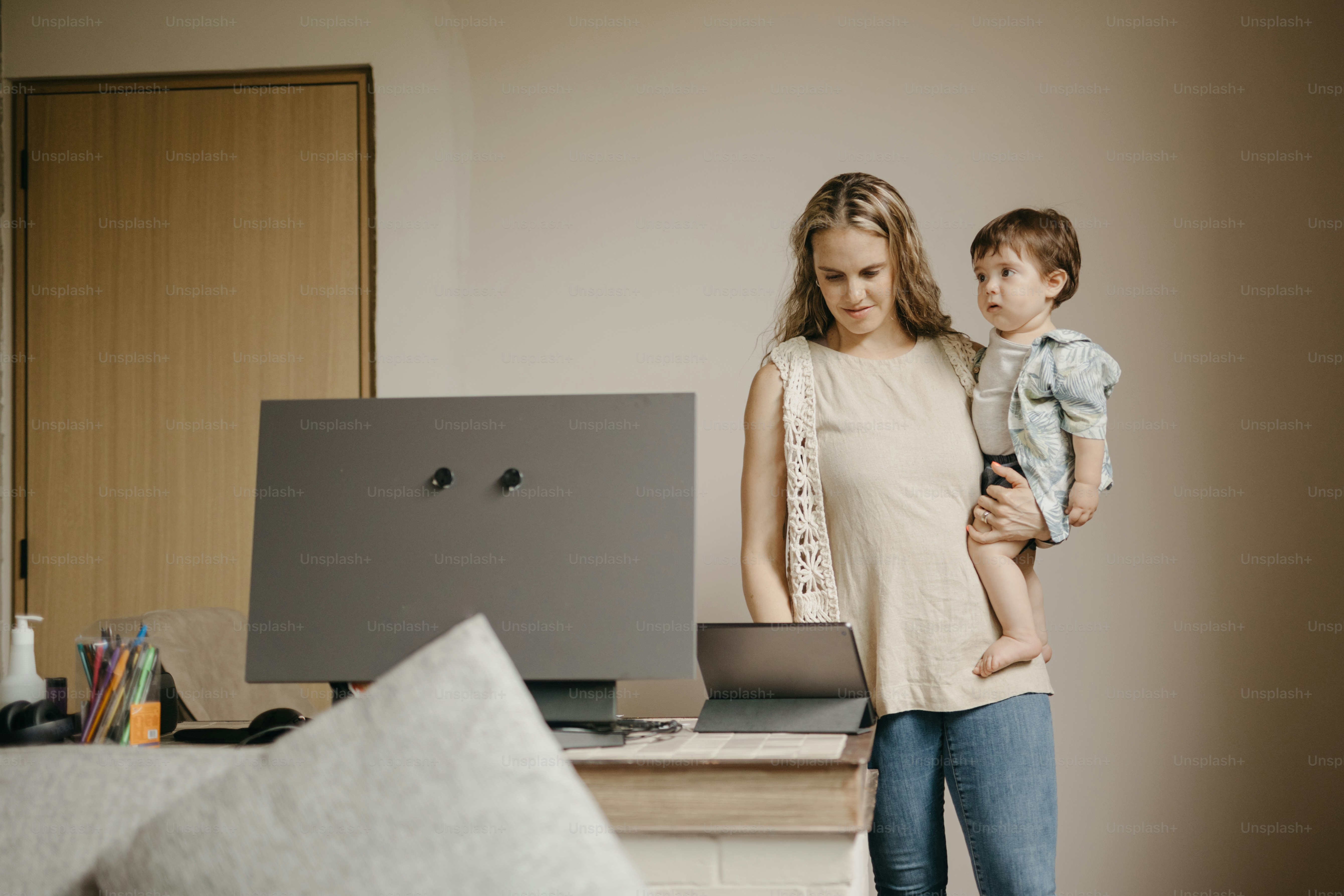 A mother works on her computer with her child. photo – Technology Image ...