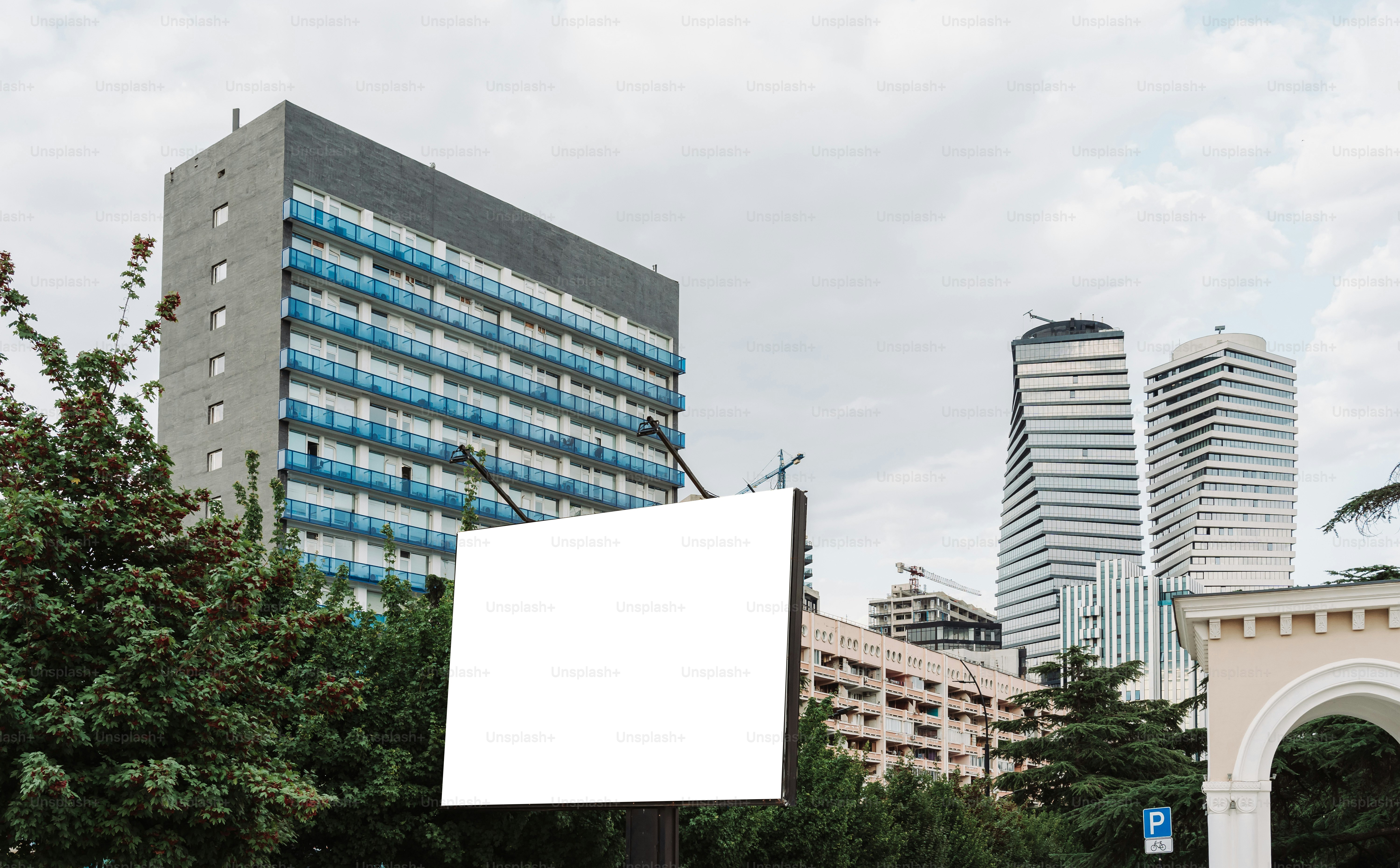 An empty billboard stands against a city skyline.