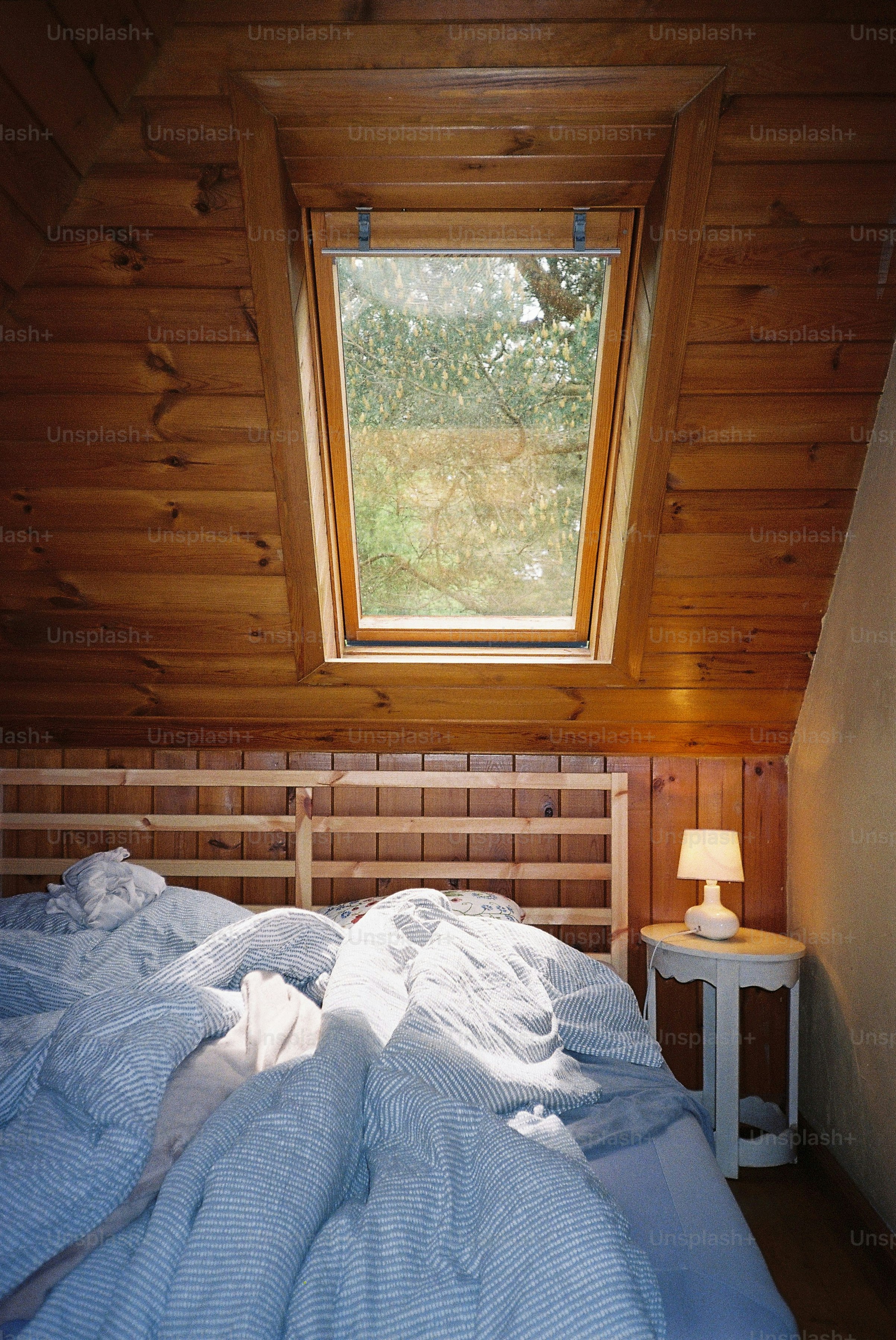 Cozy bedroom with a skylight and rumpled bed.