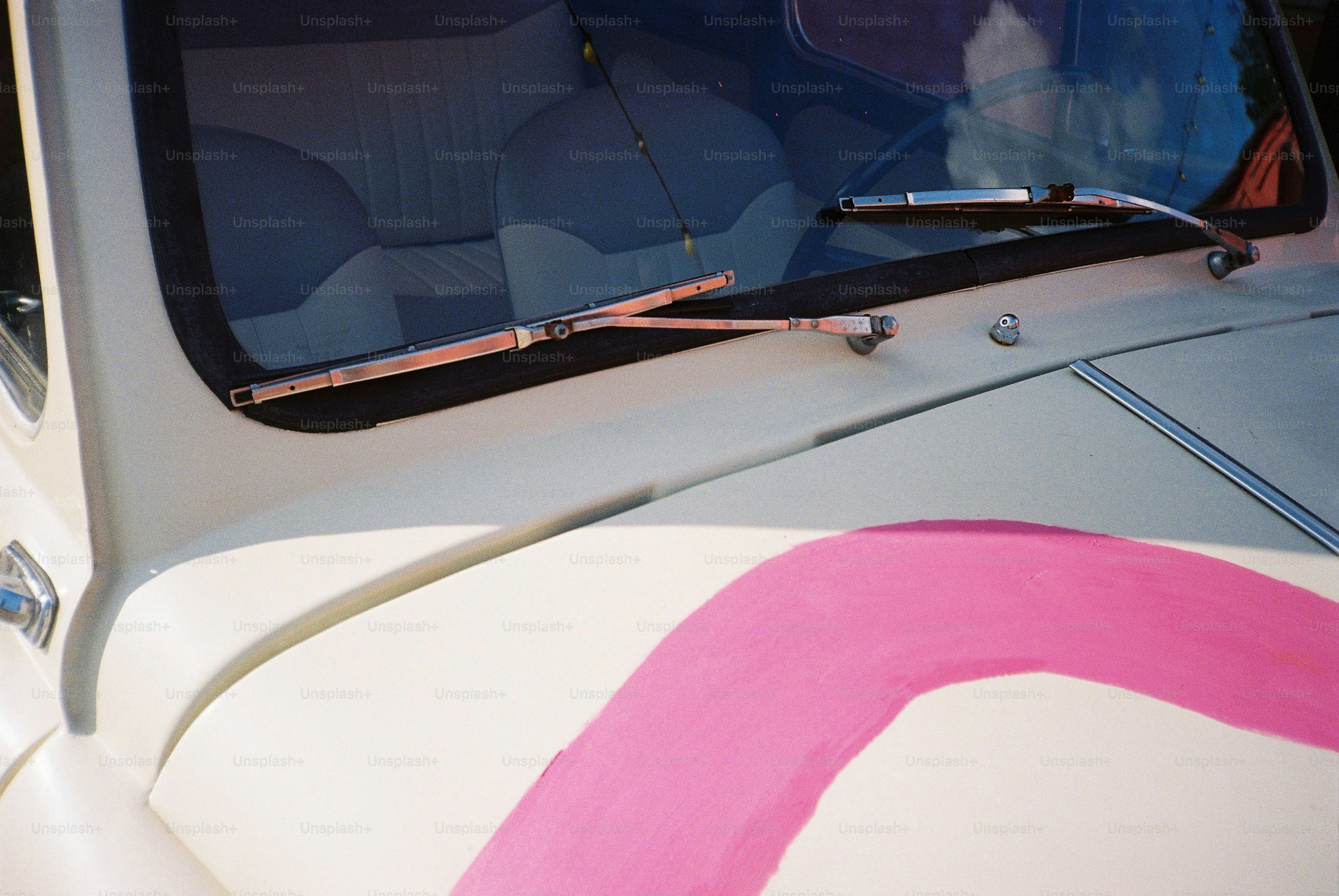 Here is a short caption for the image: a vintage car with pink detailing.