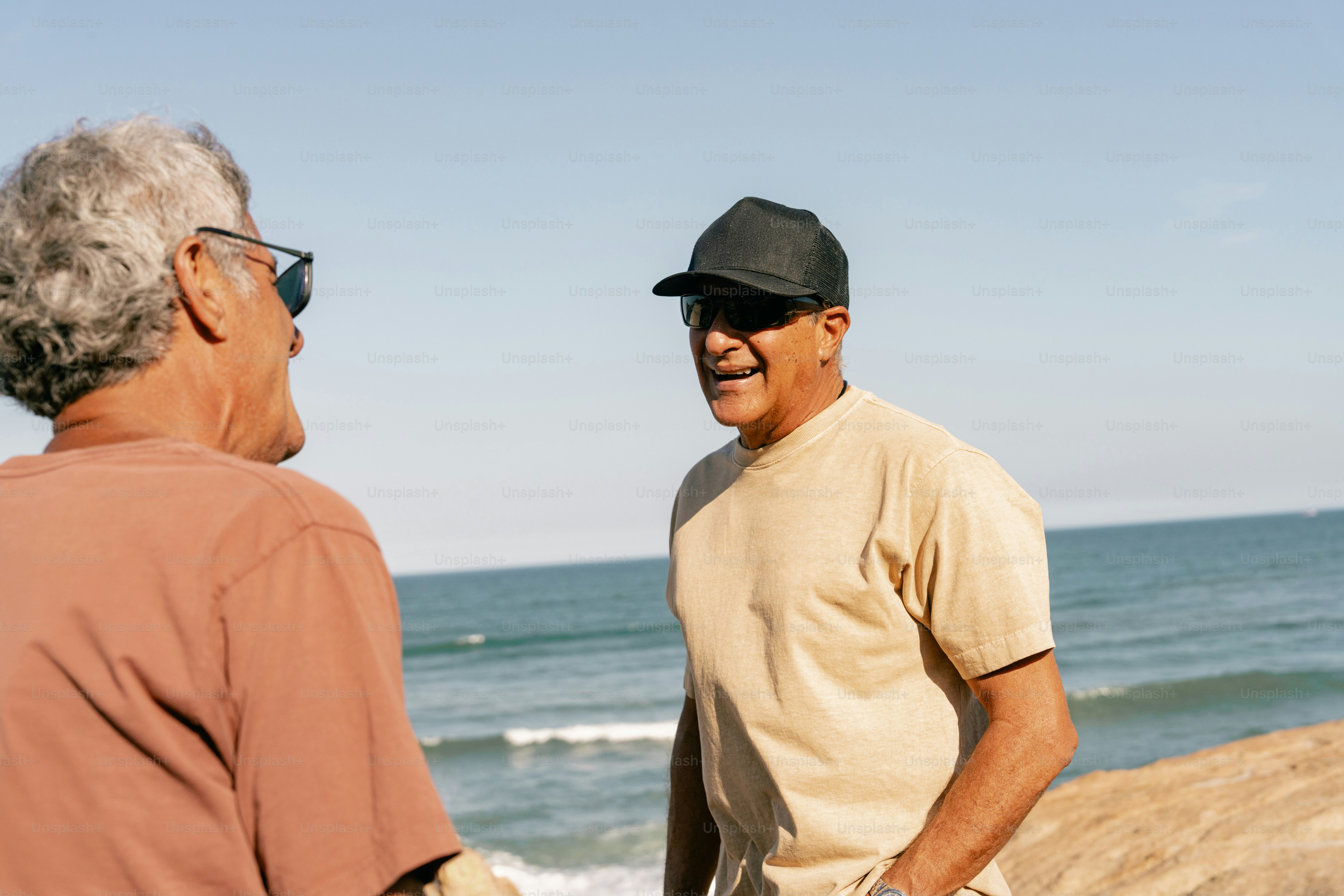 Two elderly men laughing on the beach.