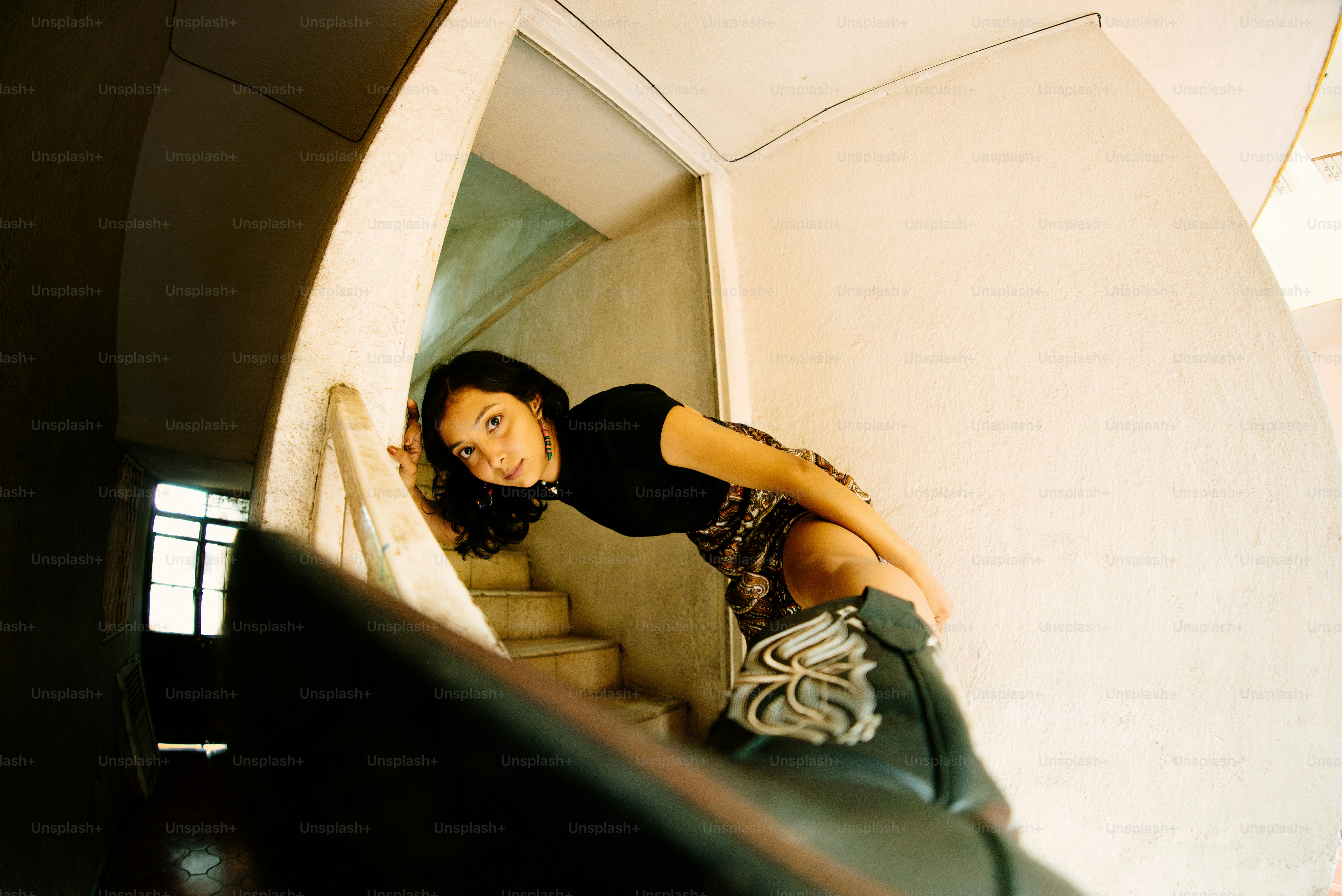 A woman leans against a staircase.