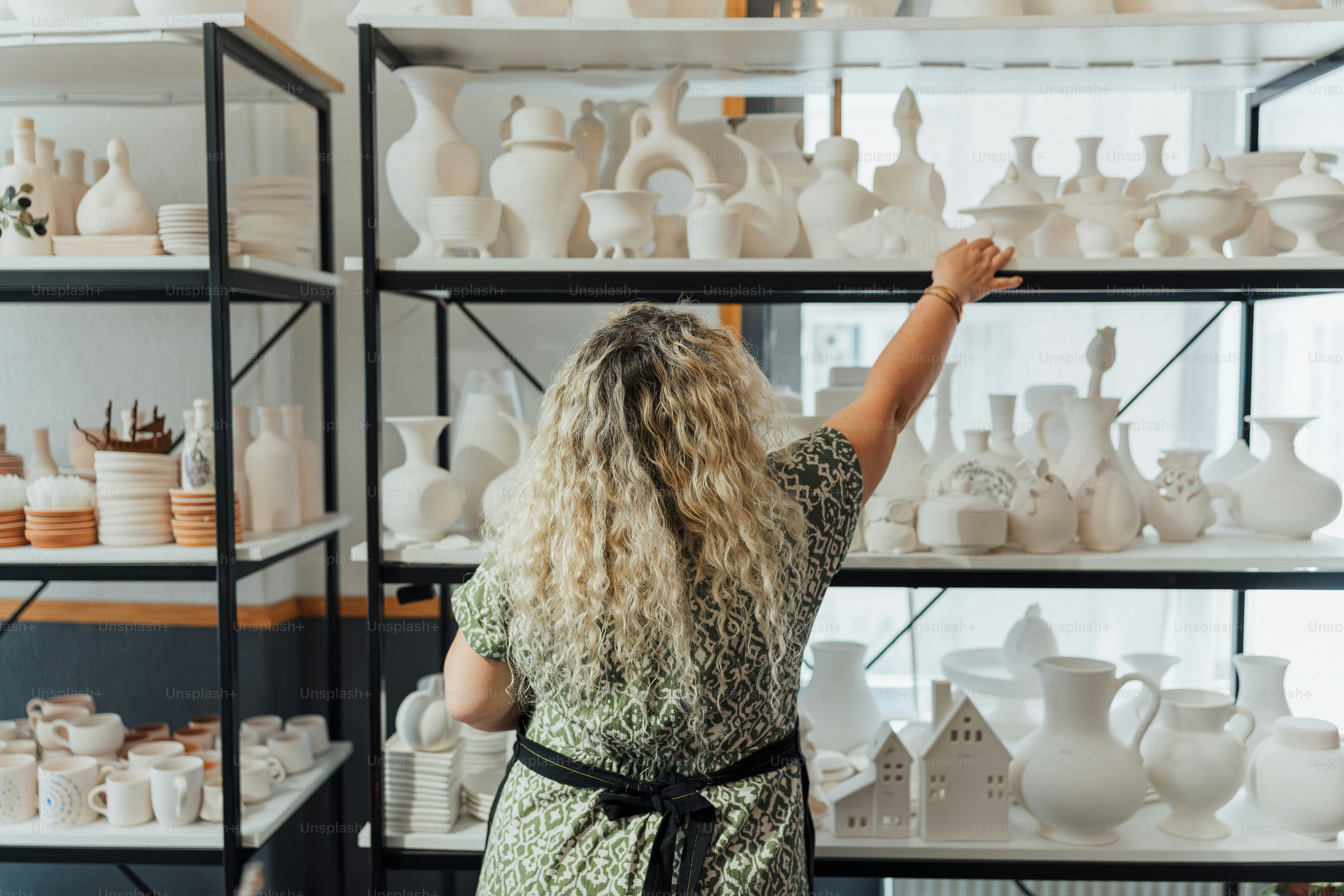 A smiling woman poses in a pottery shop. photo – Business Image on Unsplash