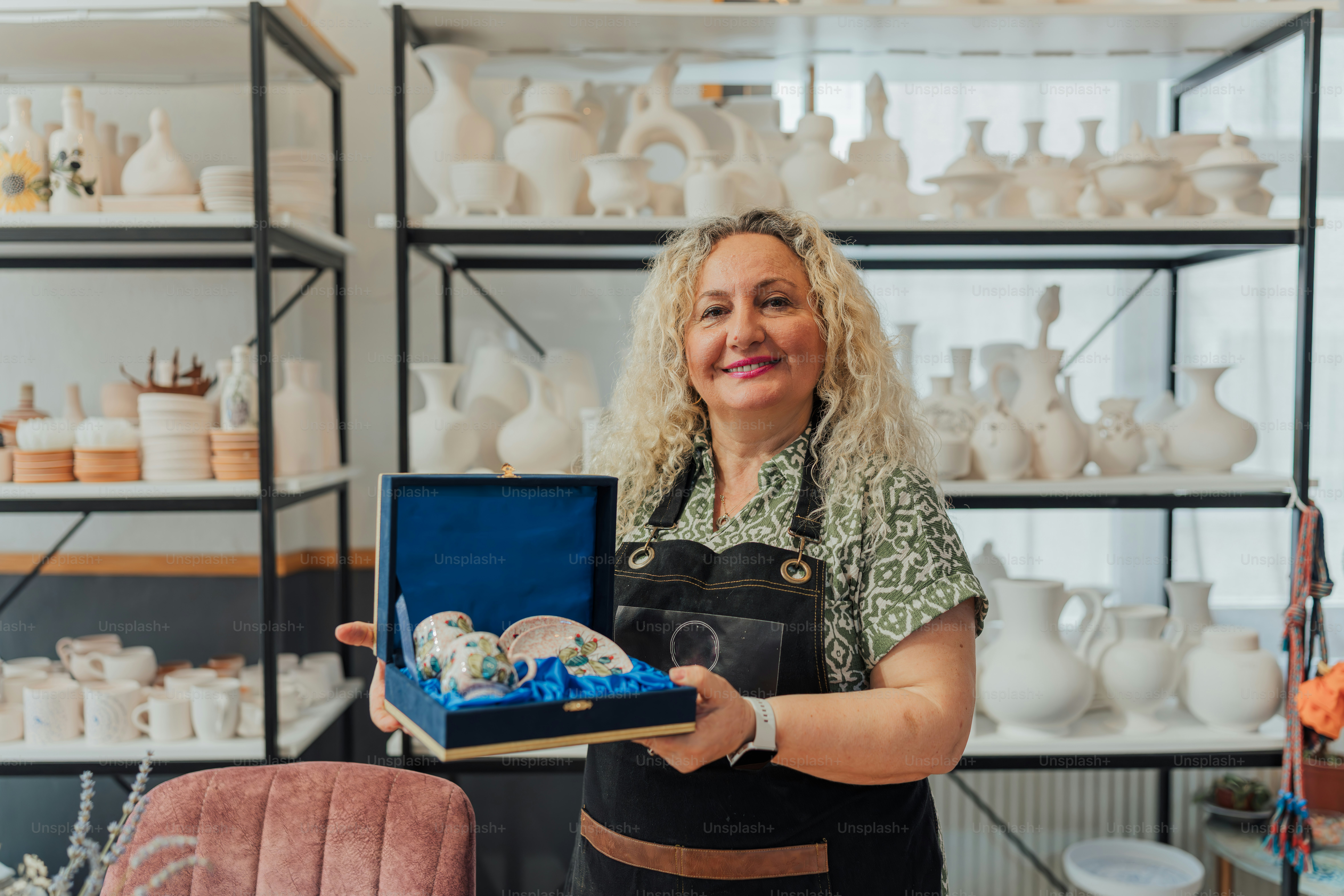 A smiling woman poses in a pottery shop. photo – Business Image on Unsplash