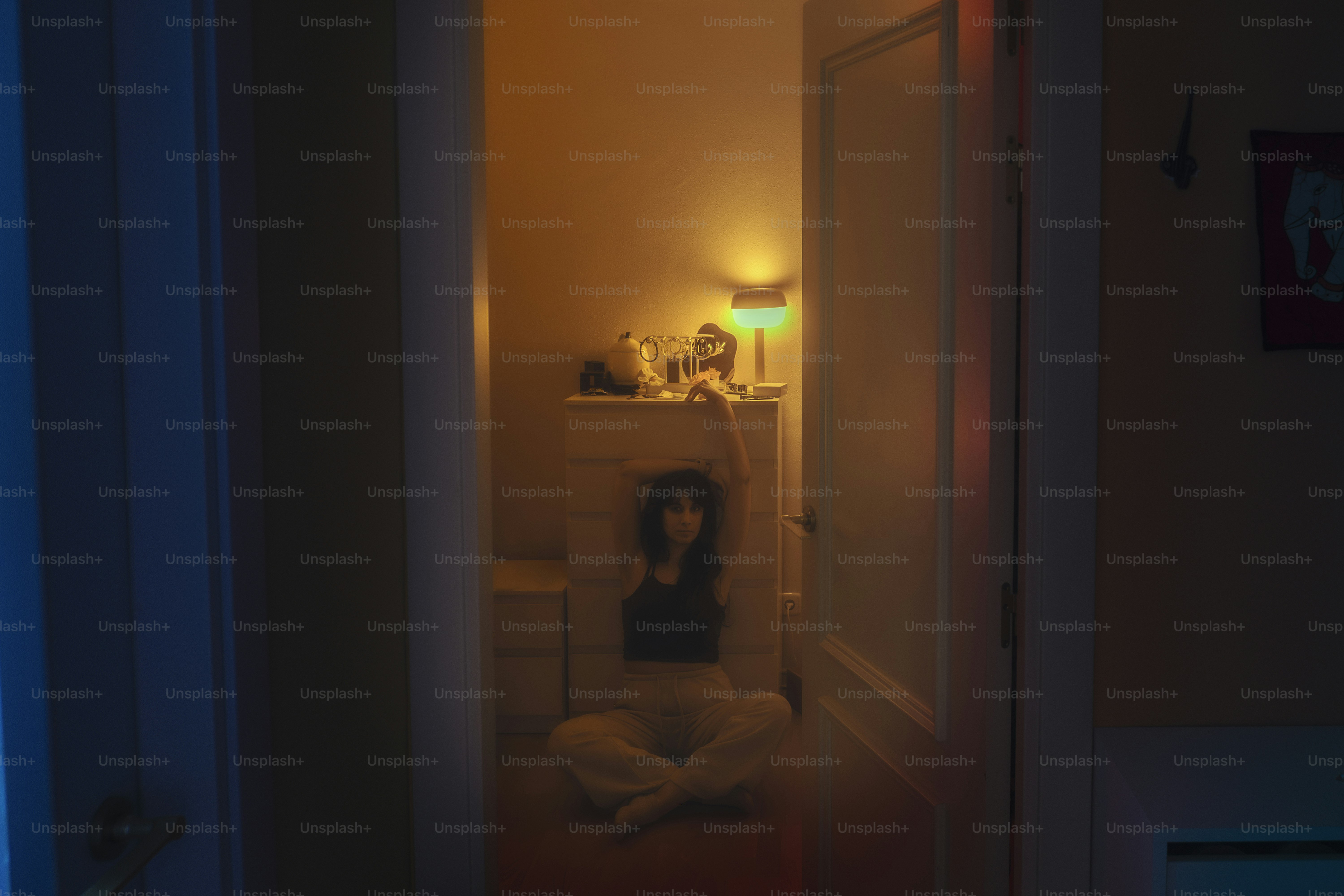 Woman sits in doorway, arms raised.