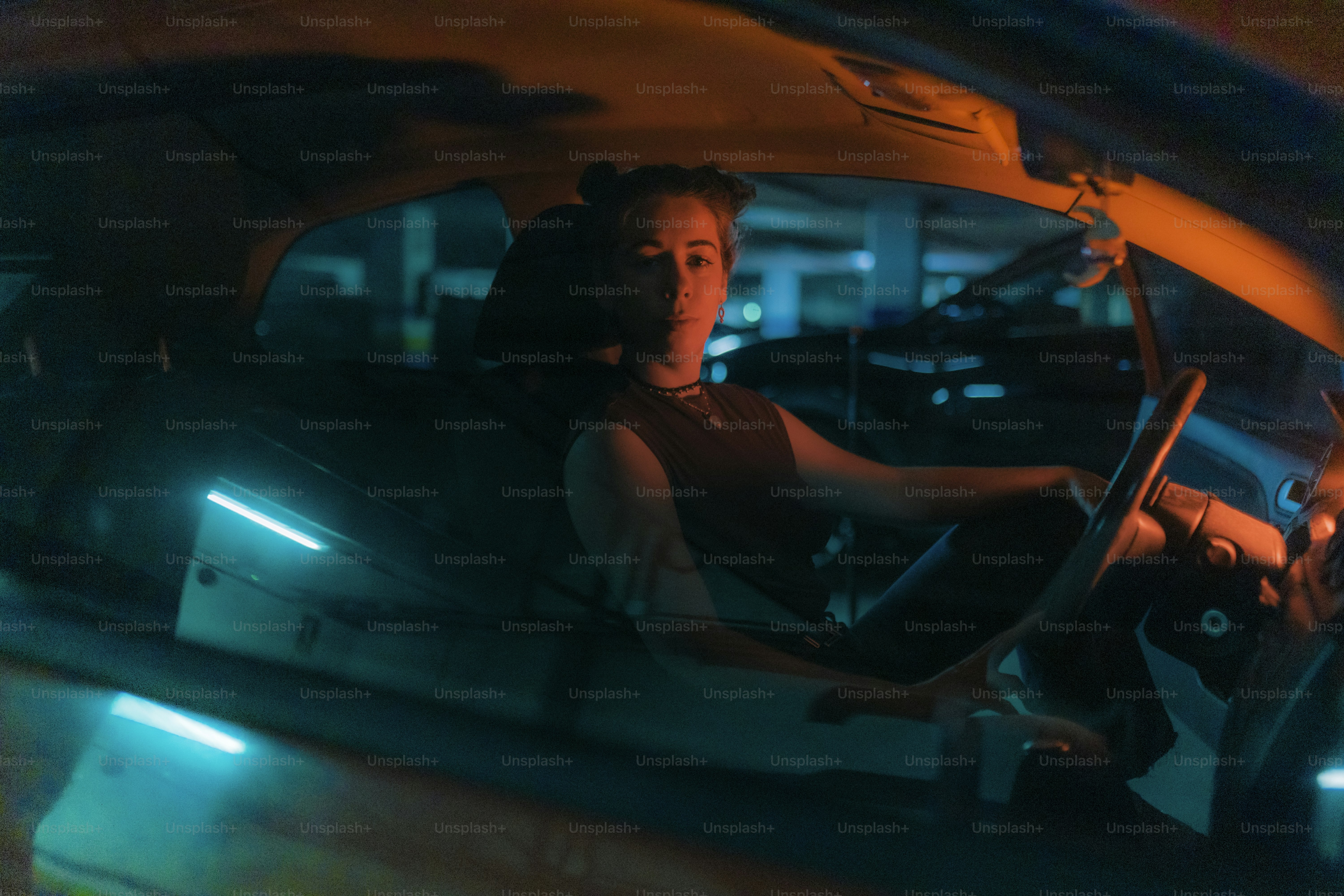 Una mujer se sienta dentro de un coche por la noche.