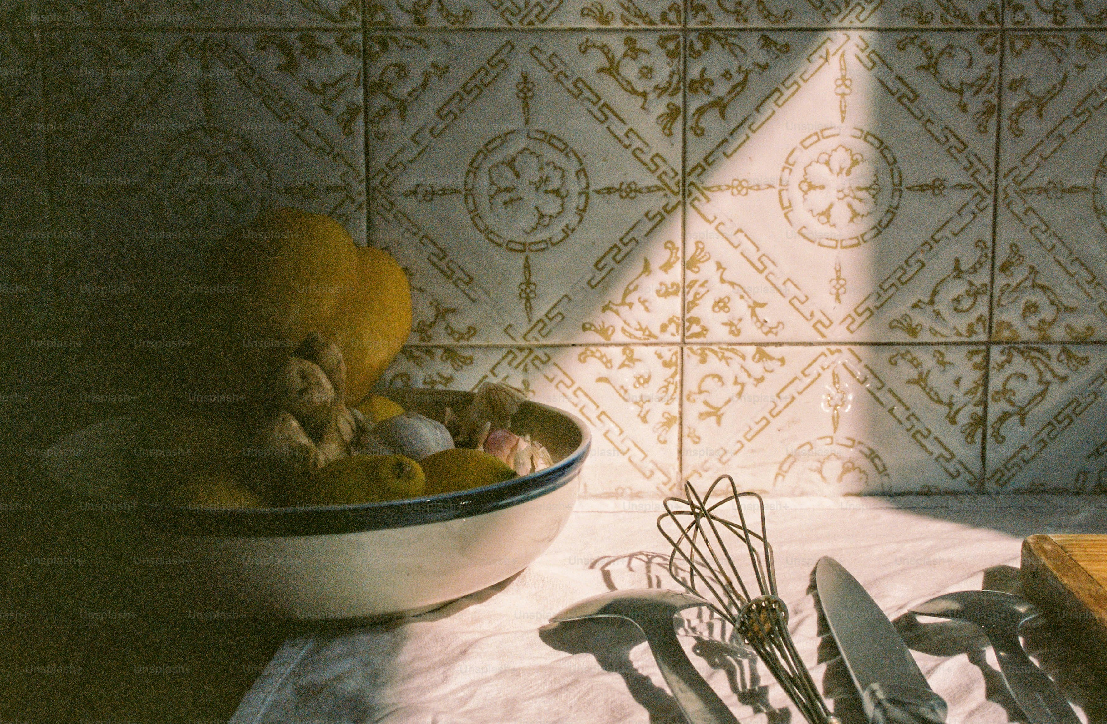 Un cuenco de frutas y utensilios sobre una mesa.