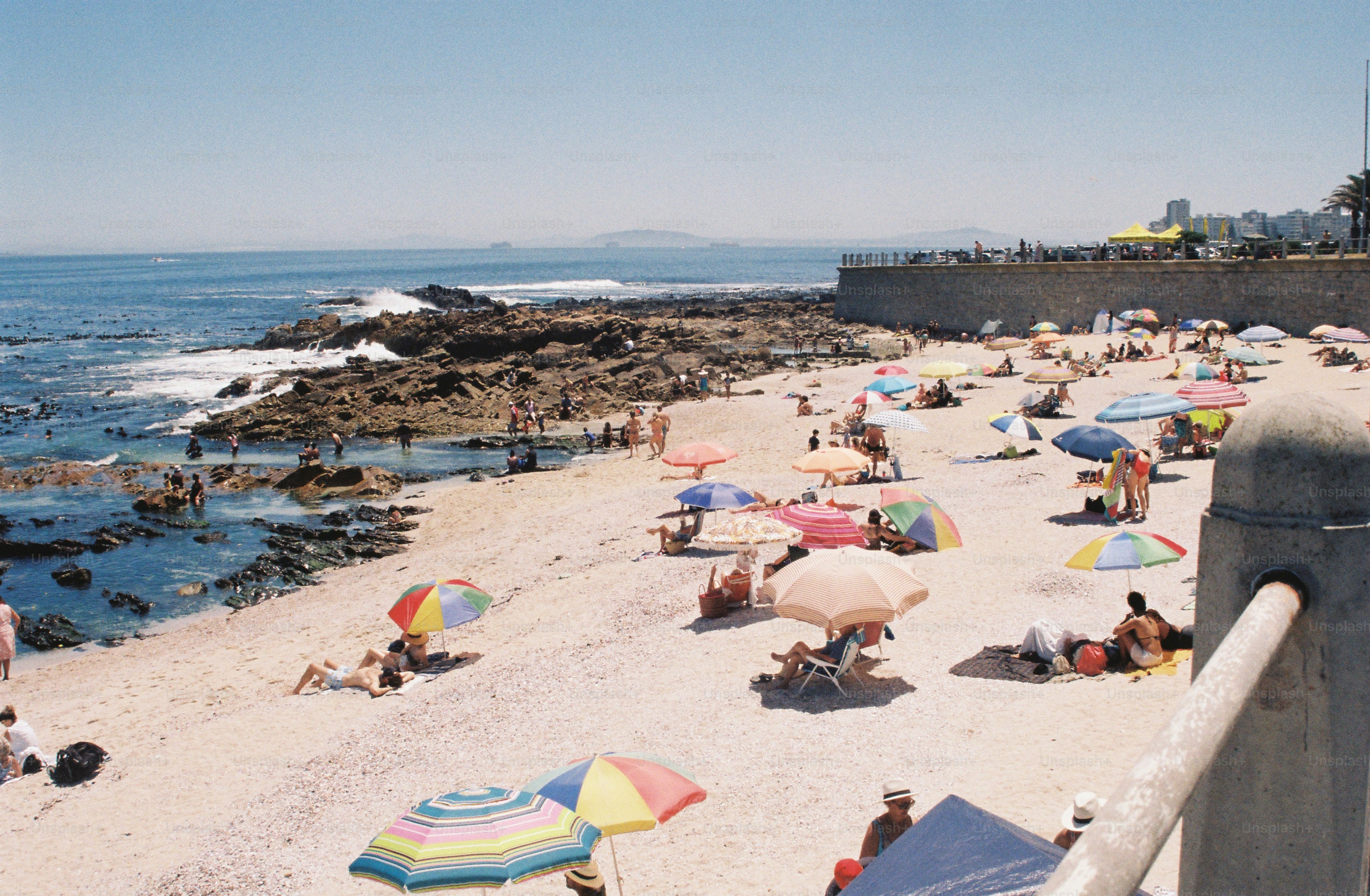 La gente se relaja en una playa soleada con sombrillas.