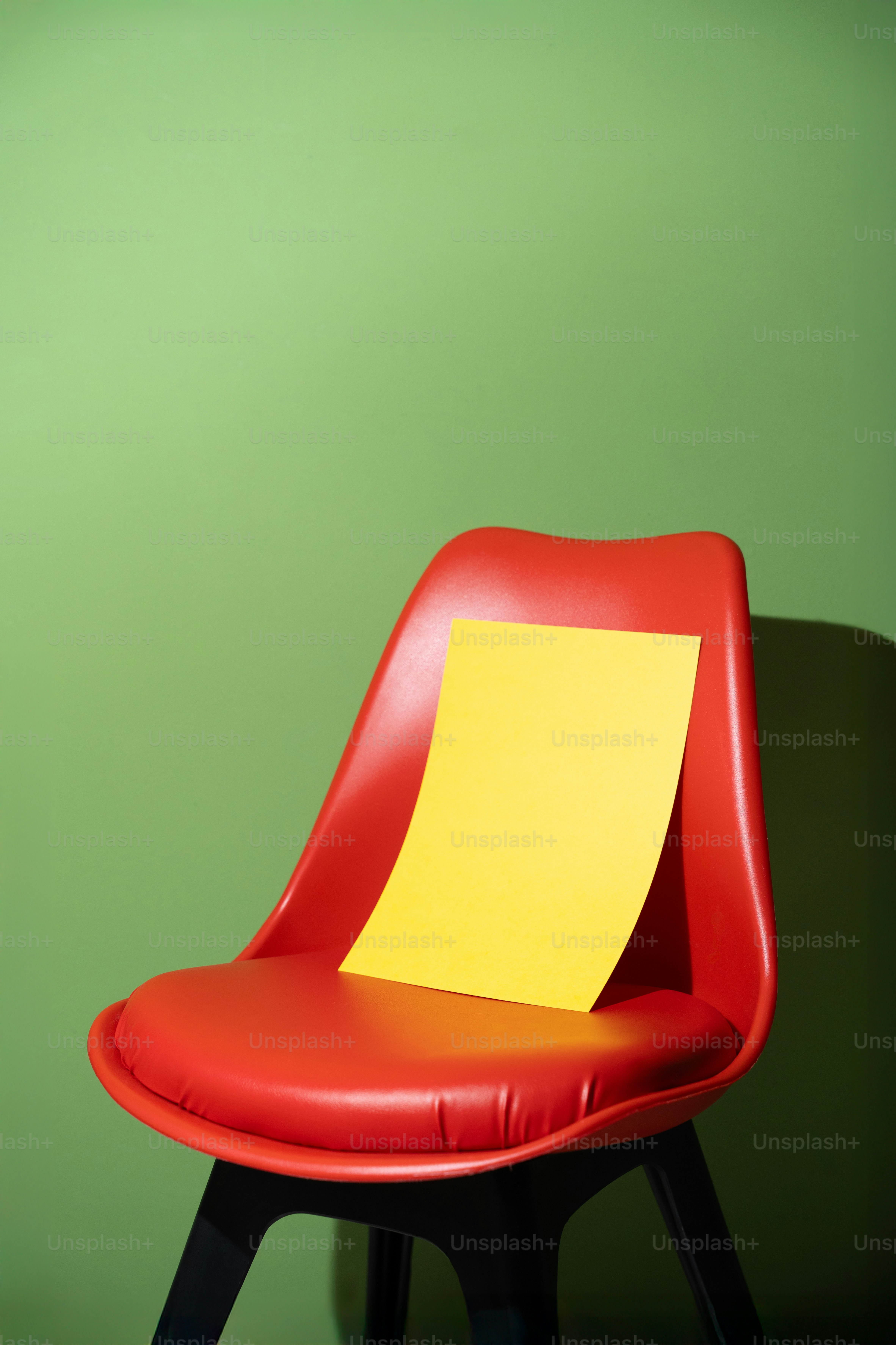 A yellow paper rests on a red chair.