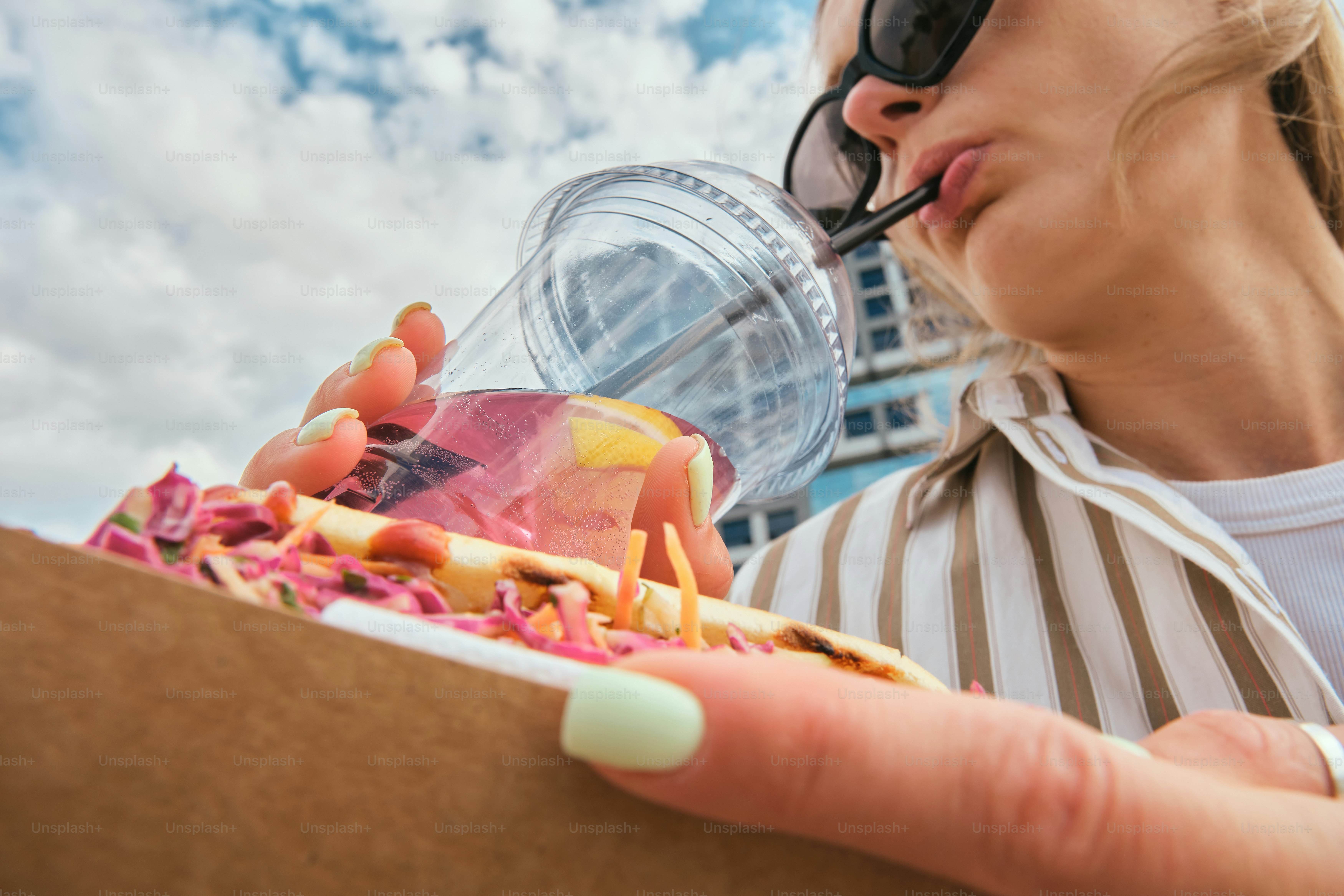 Woman enjoys food and a drink outdoors.