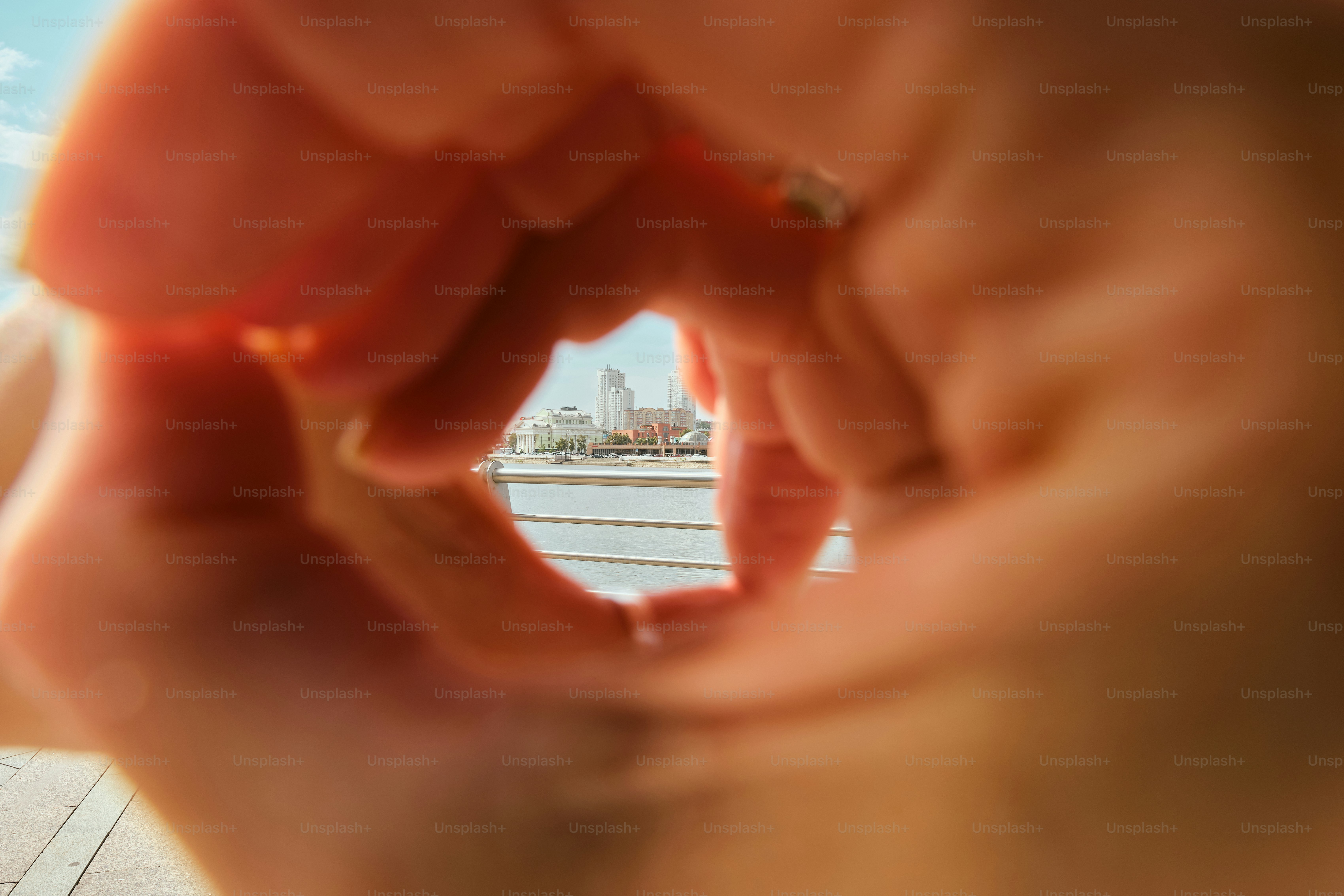 Hands form a circle, framing a distant city view.