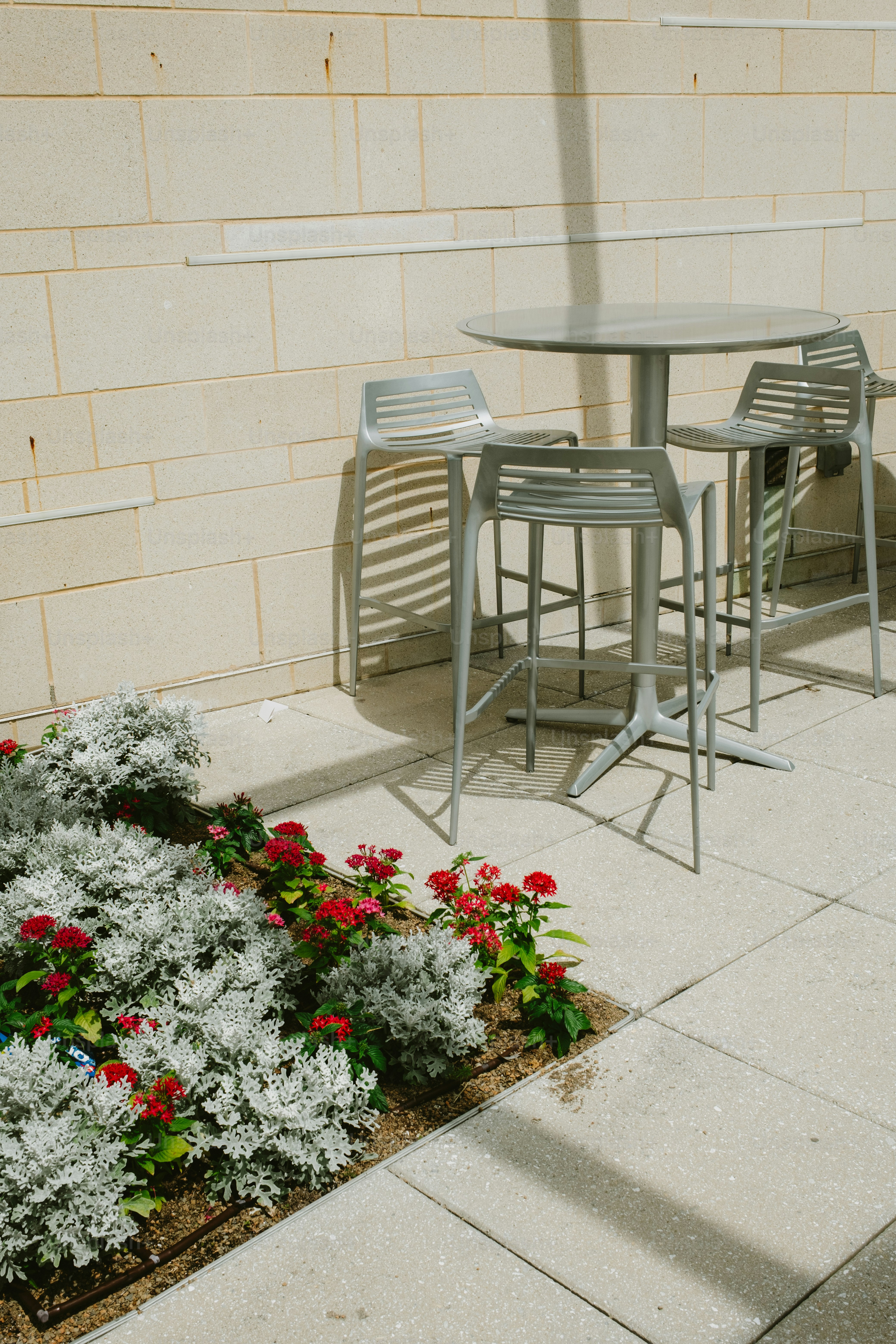 Outdoor seating beside flowers and a wall.