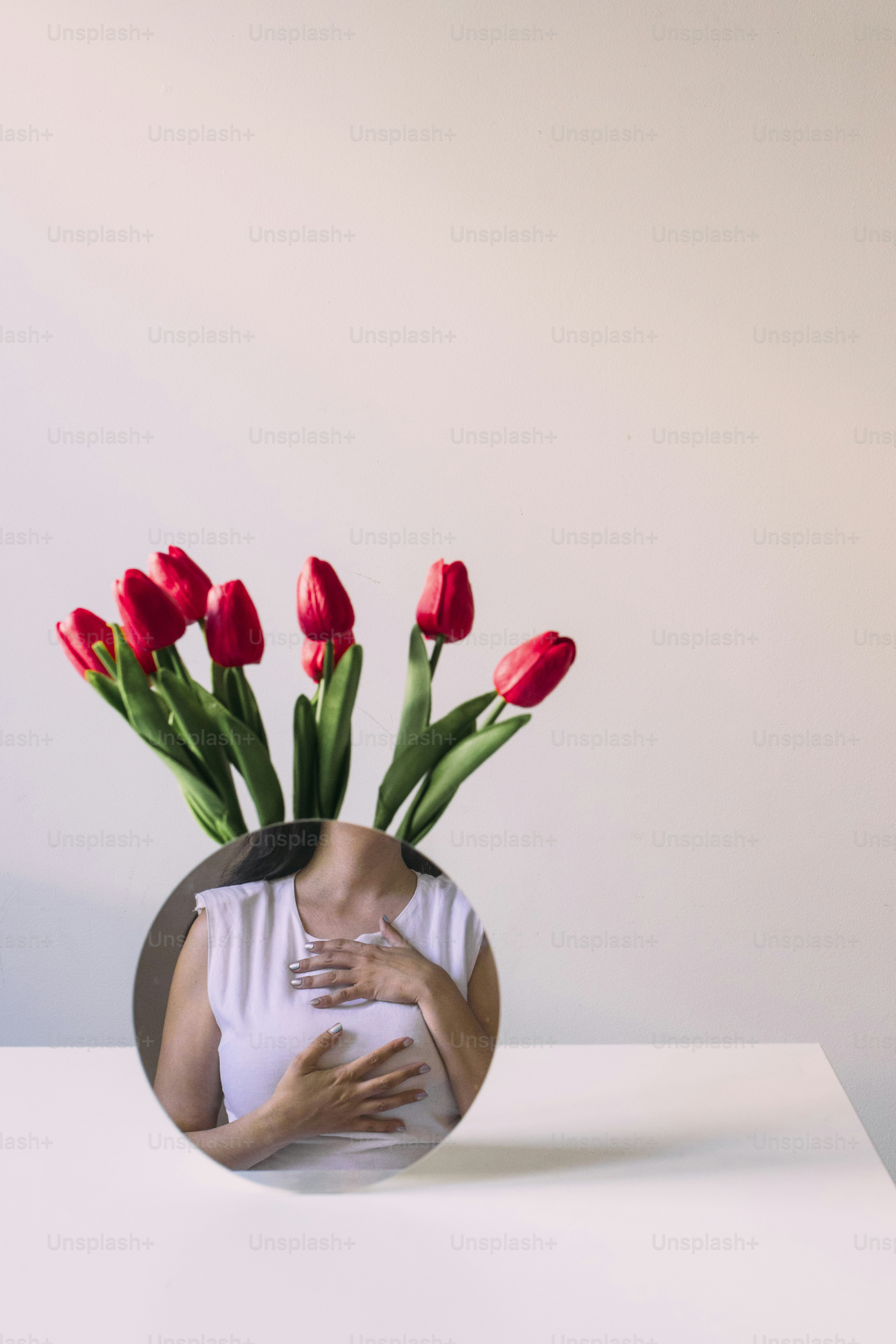 La femme touche la poitrine avec des fleurs en arrière-plan.