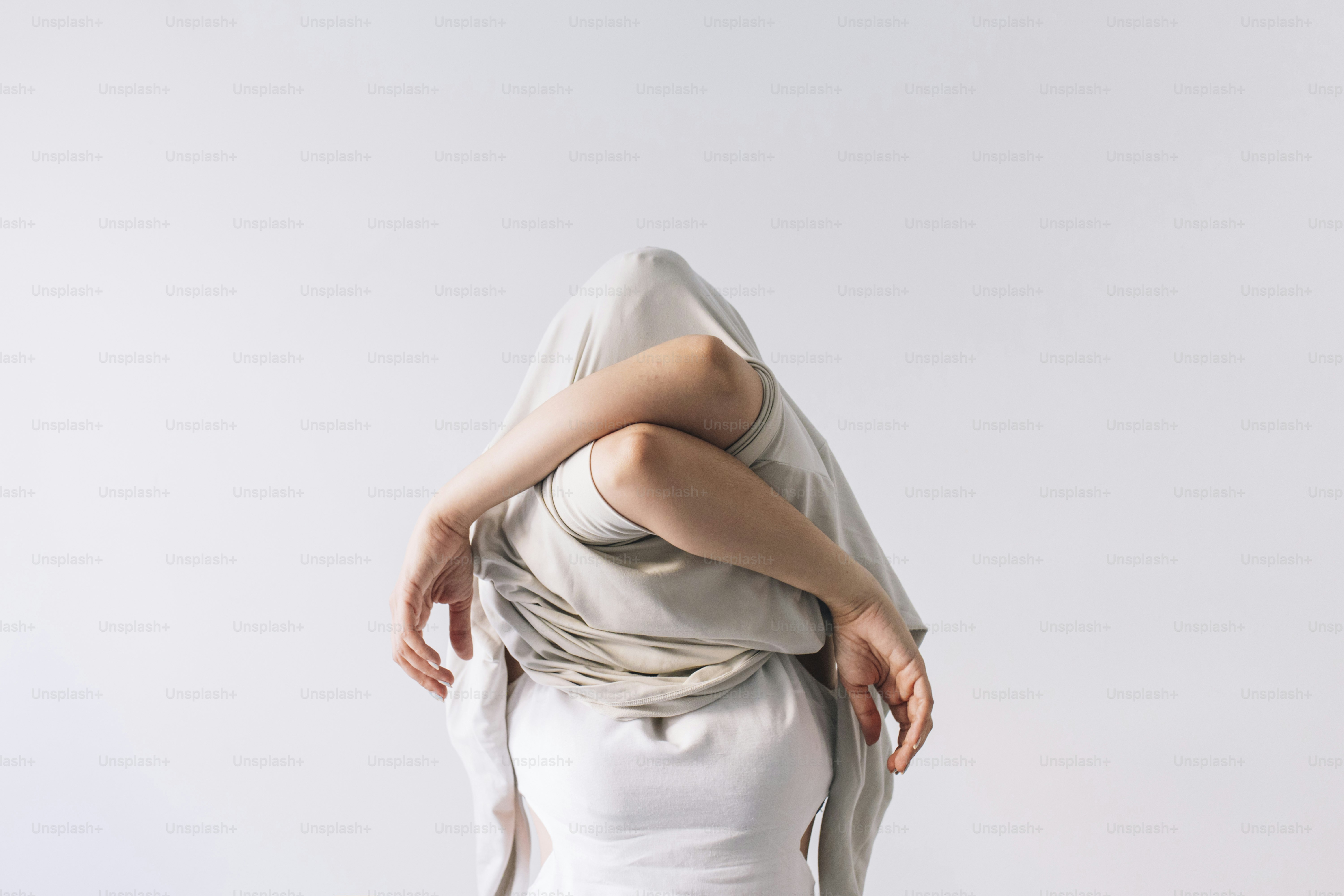 Personne recouverte d’un drap, les bras croisés.