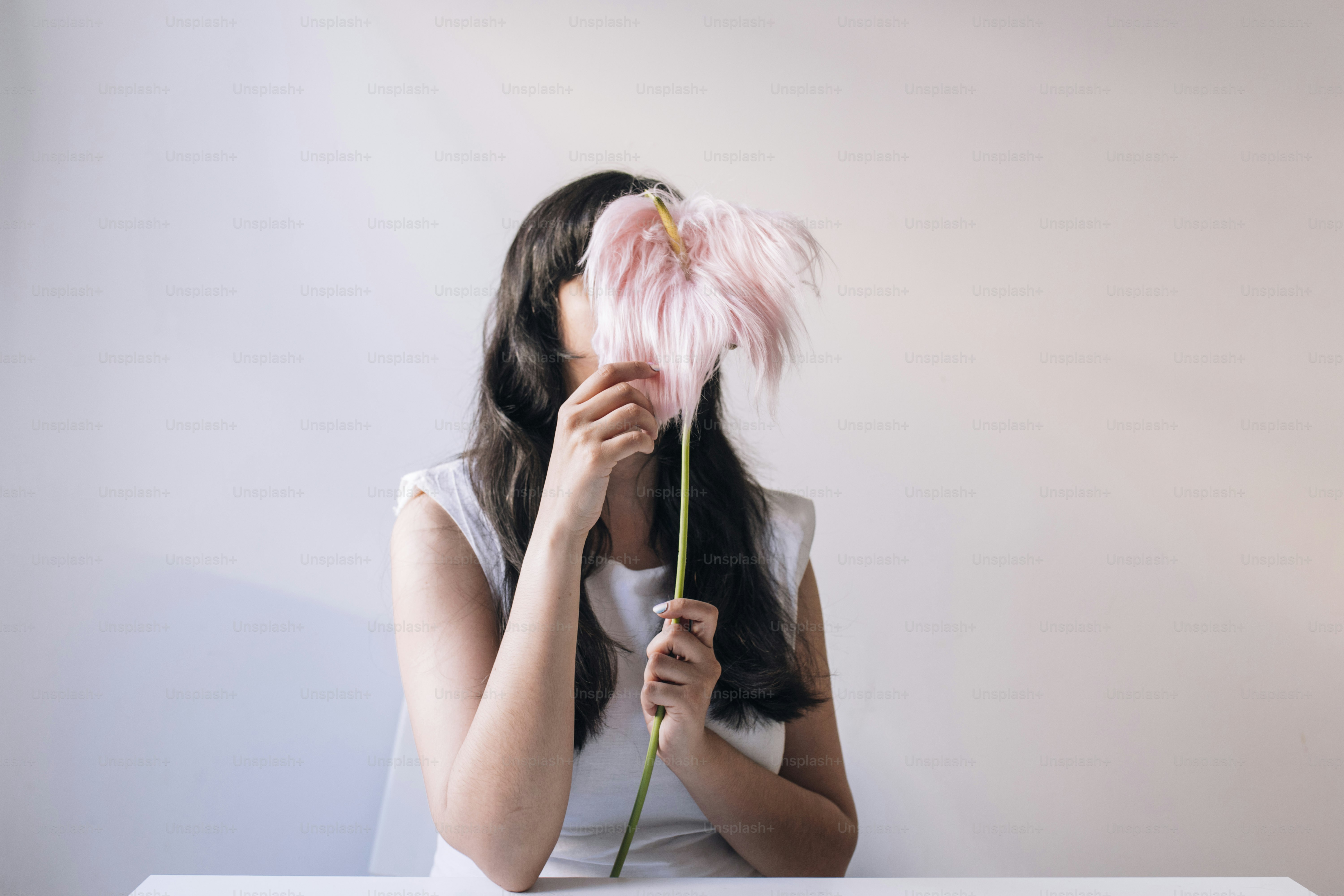 Une femme cache son visage derrière une fleur.