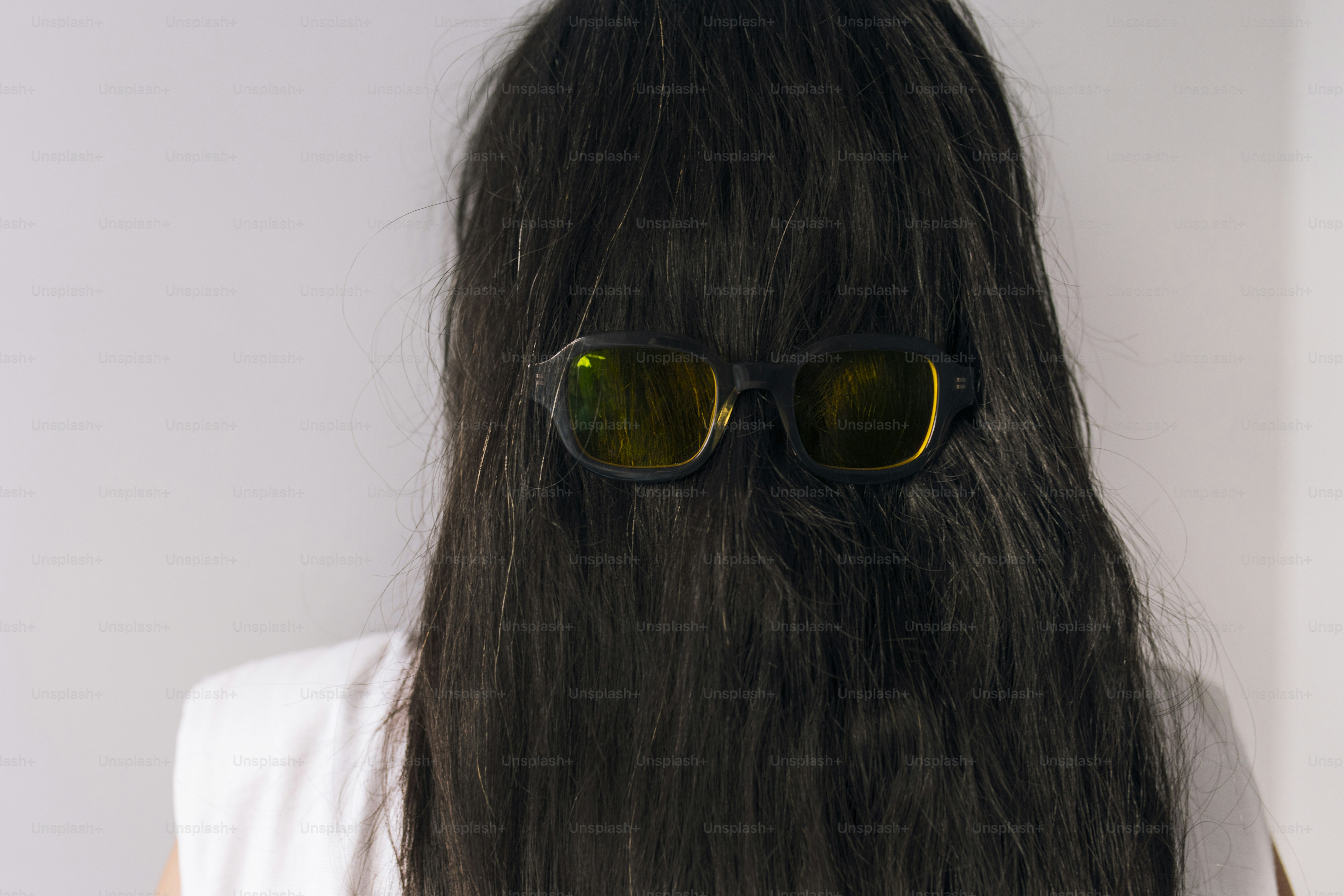 Les lunettes de soleil reposent sur les cheveux de la personne.