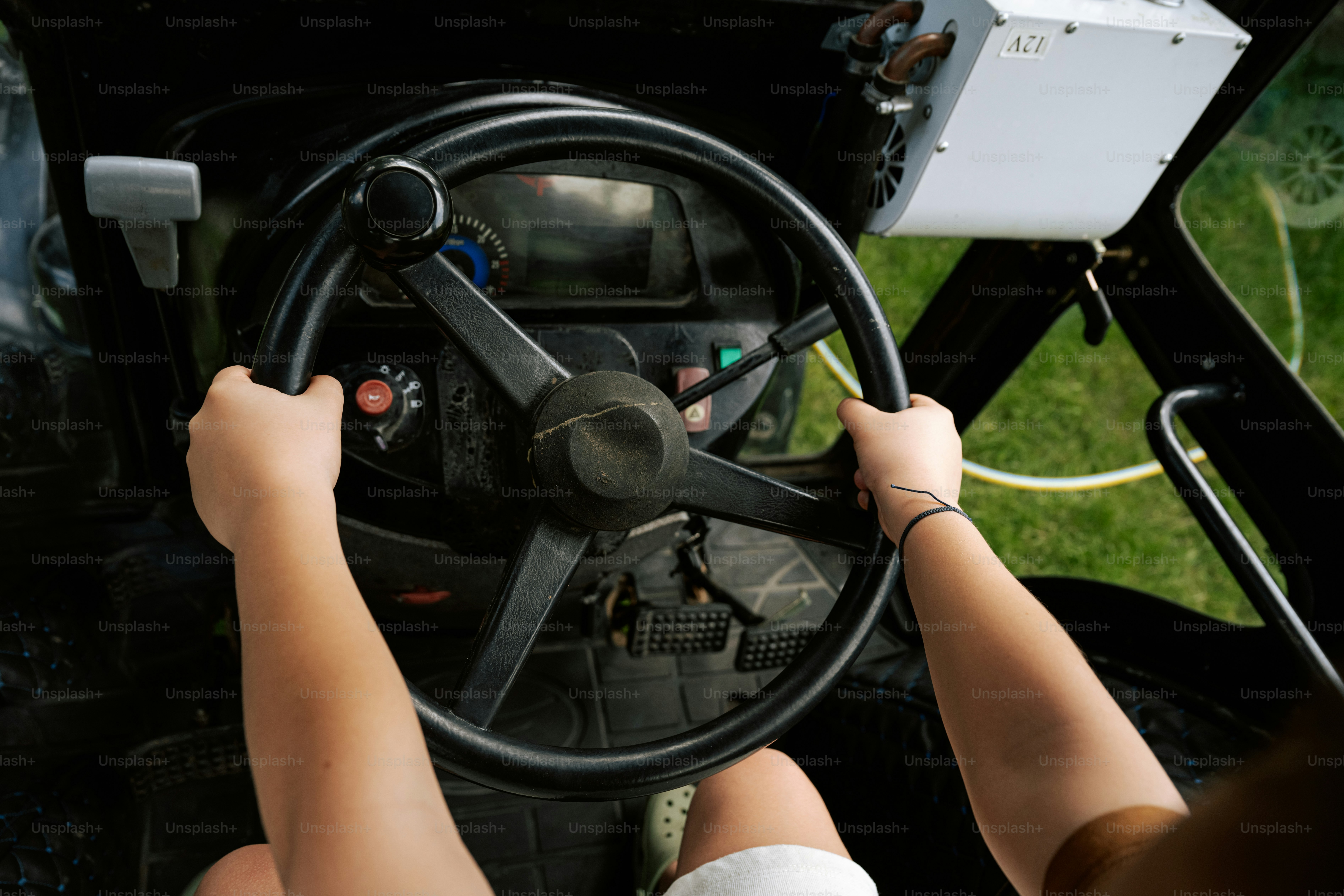 Hands are gripping the steering wheel of a vehicle.