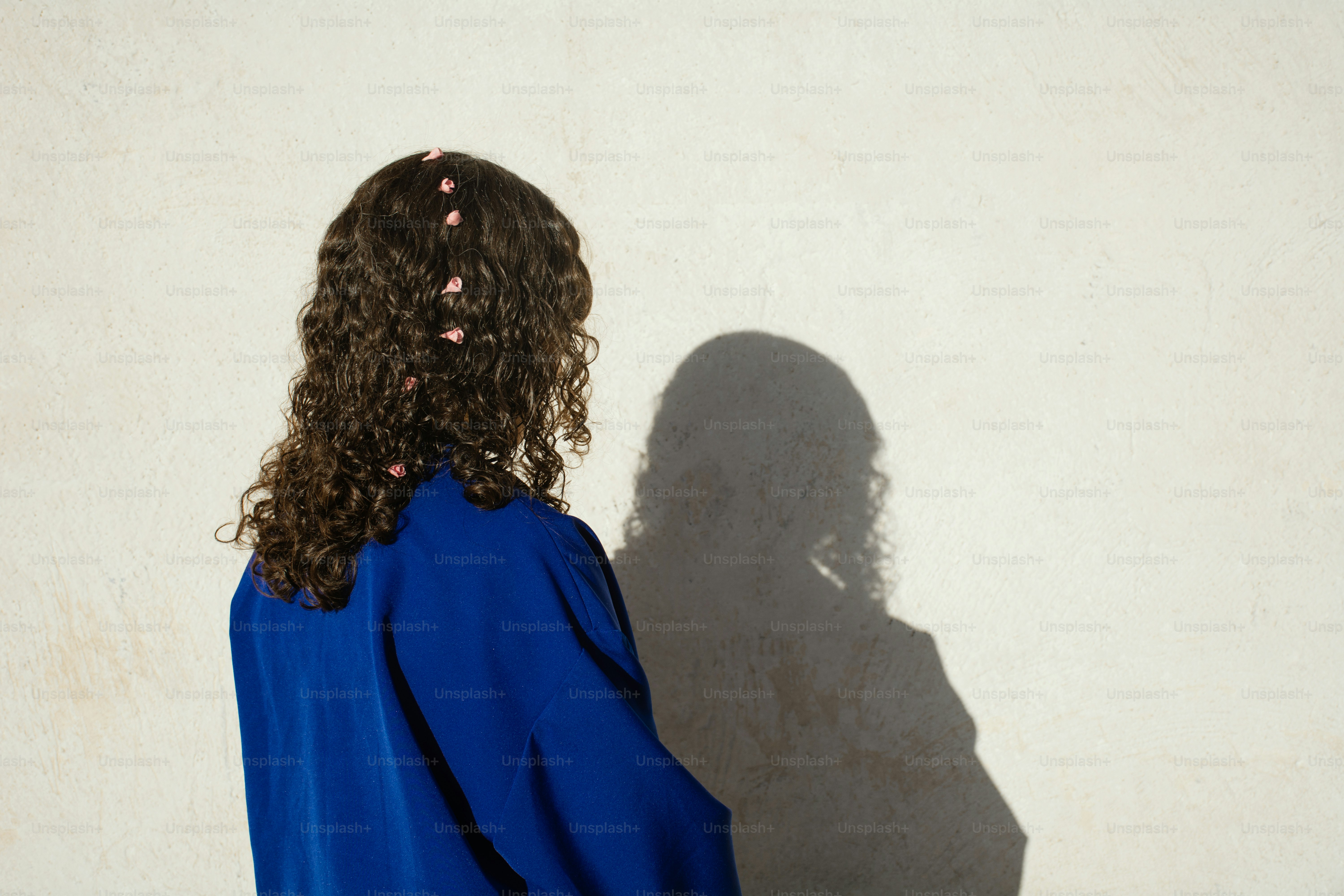 A person stands in front of a white wall.