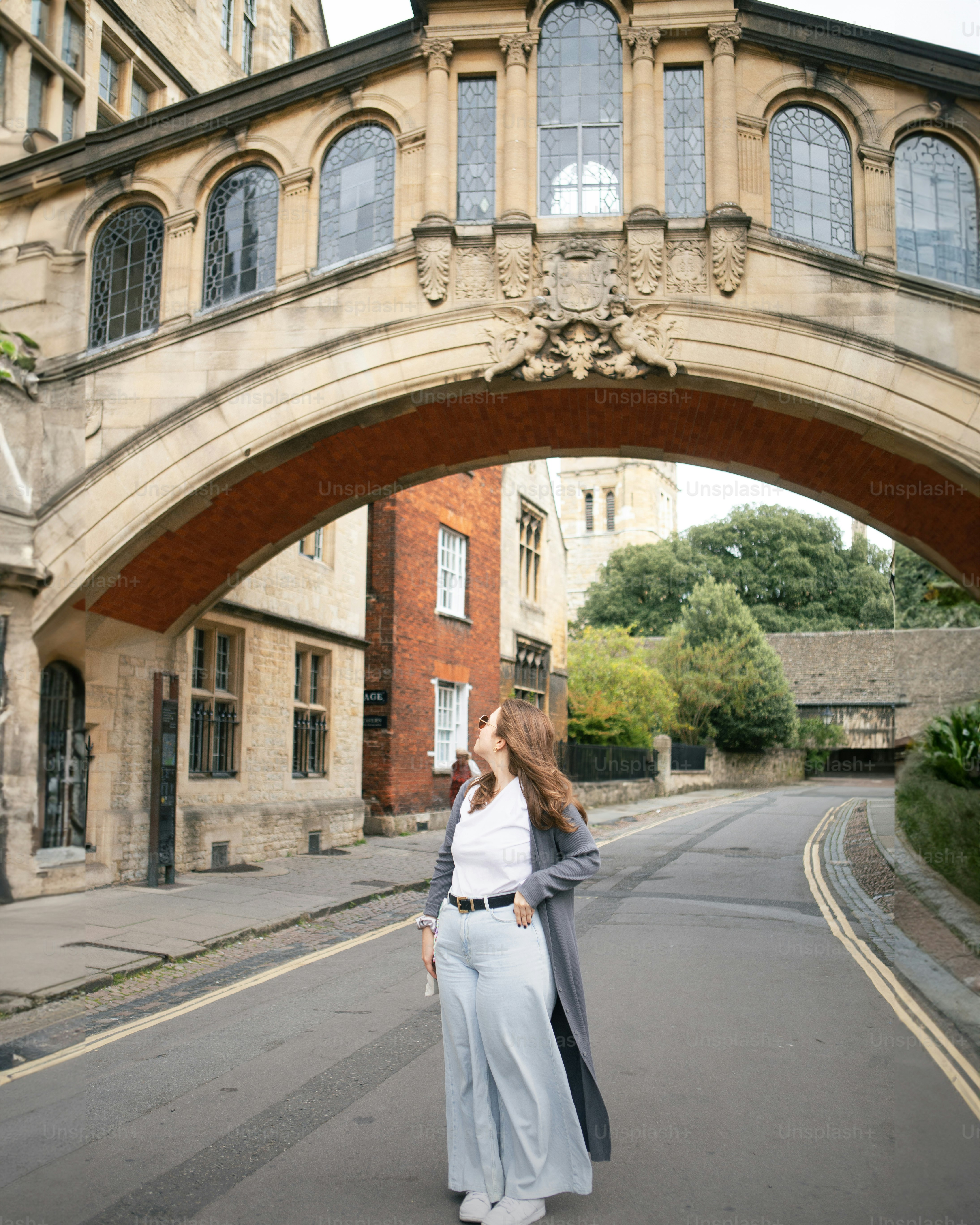 Woman posing under a bridge on a street.